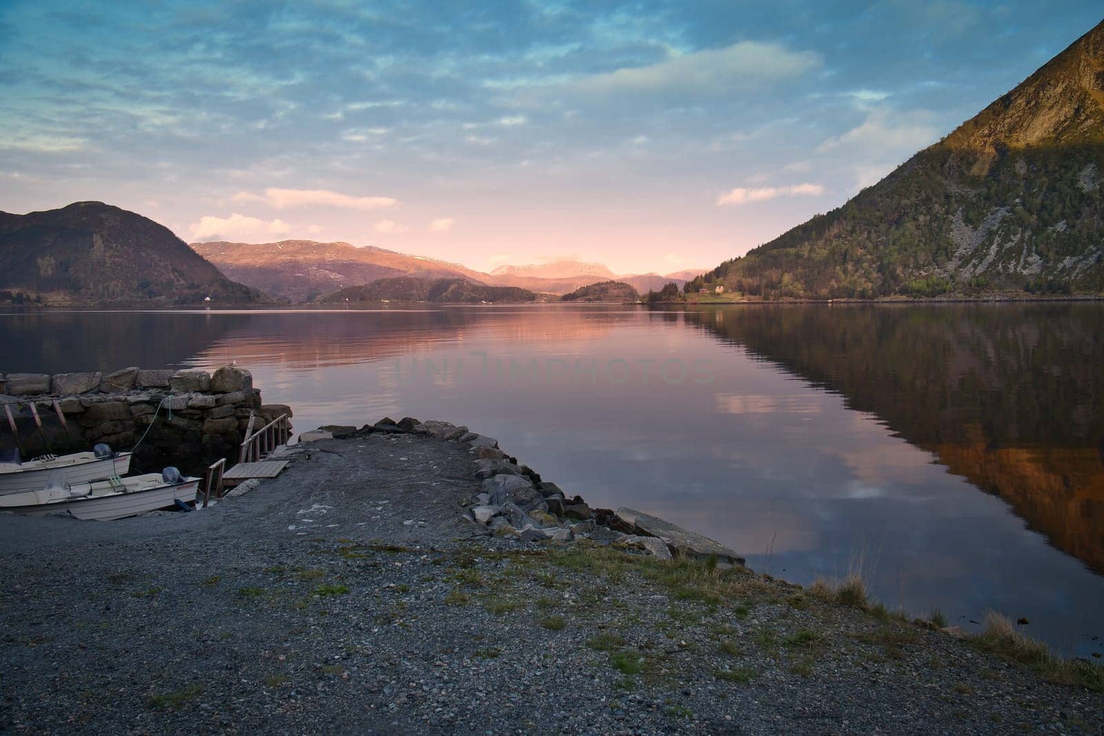 Norwegian landscape. View over a small harbor to the fjord at sunset behind the mountain. Scandinavian nature