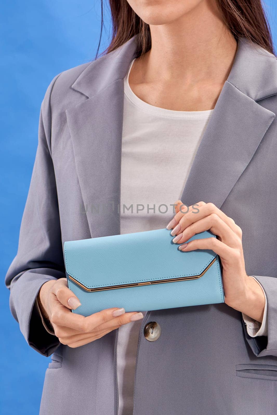 Women's hands hold a blue handbag. High quality photo