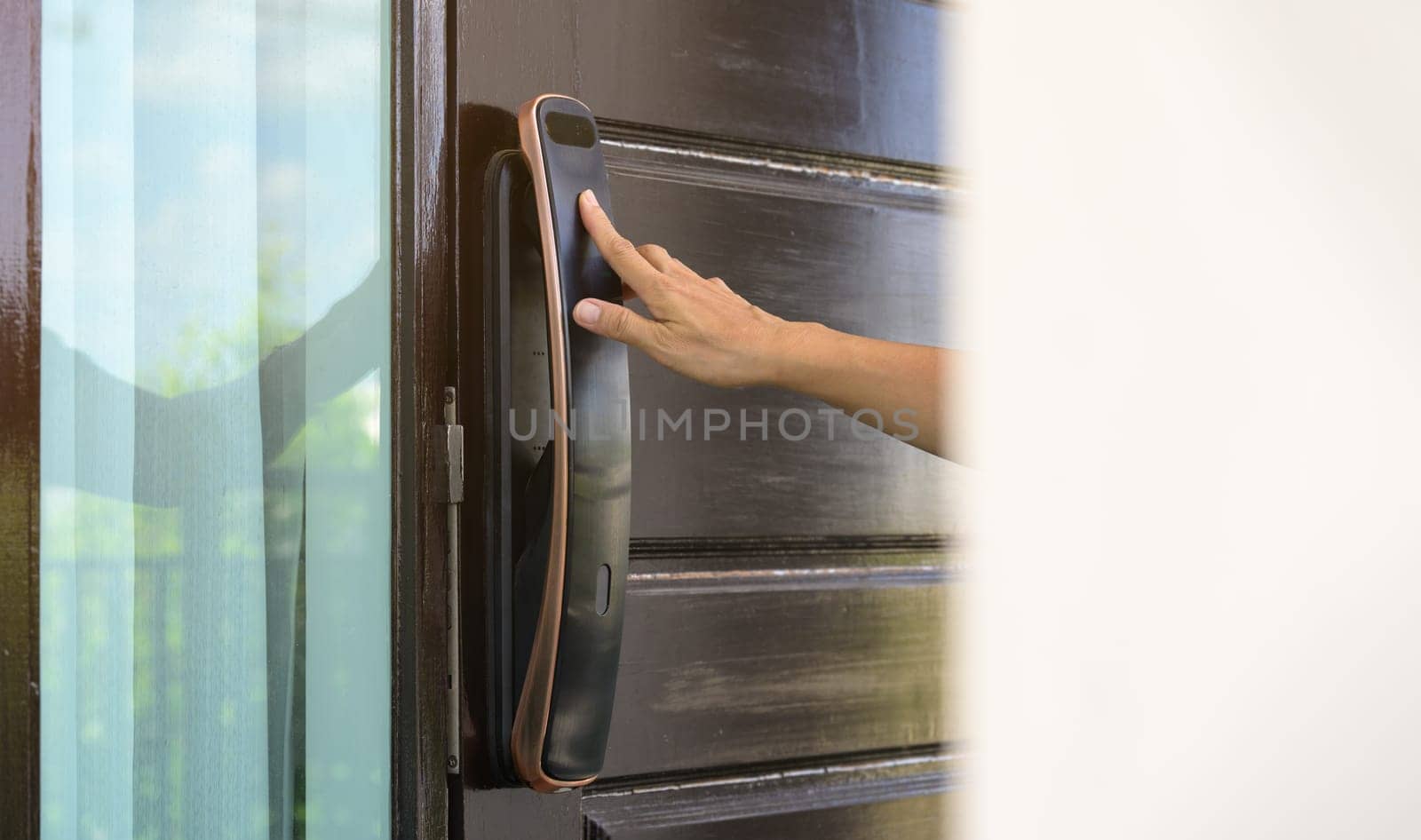 Female hand opening a door with fingerprint scanning of smart digital electronic door lock at home or apartment. Security keyless access control concept.