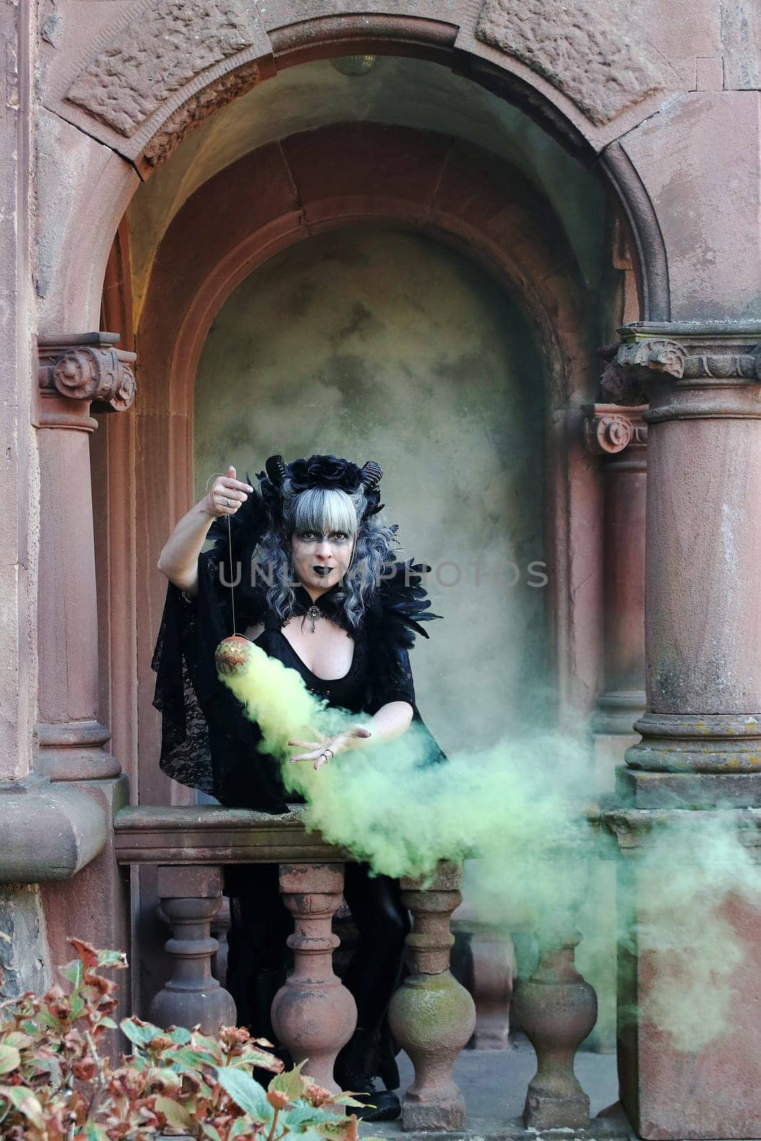 A woman dressed as an evil witch conjures with smoke