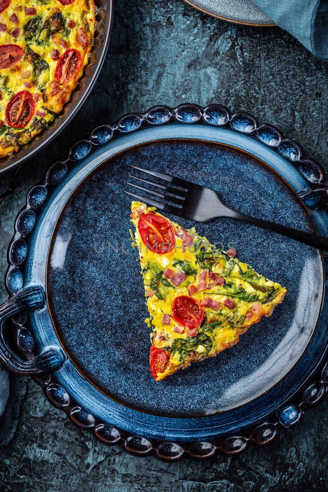 Homemade frittata with spinach, curd cheese, bacon, onion and green onions