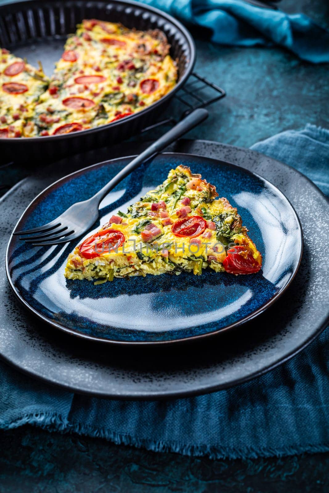 Homemade frittata with spinach, curd cheese, bacon, onion and green onions