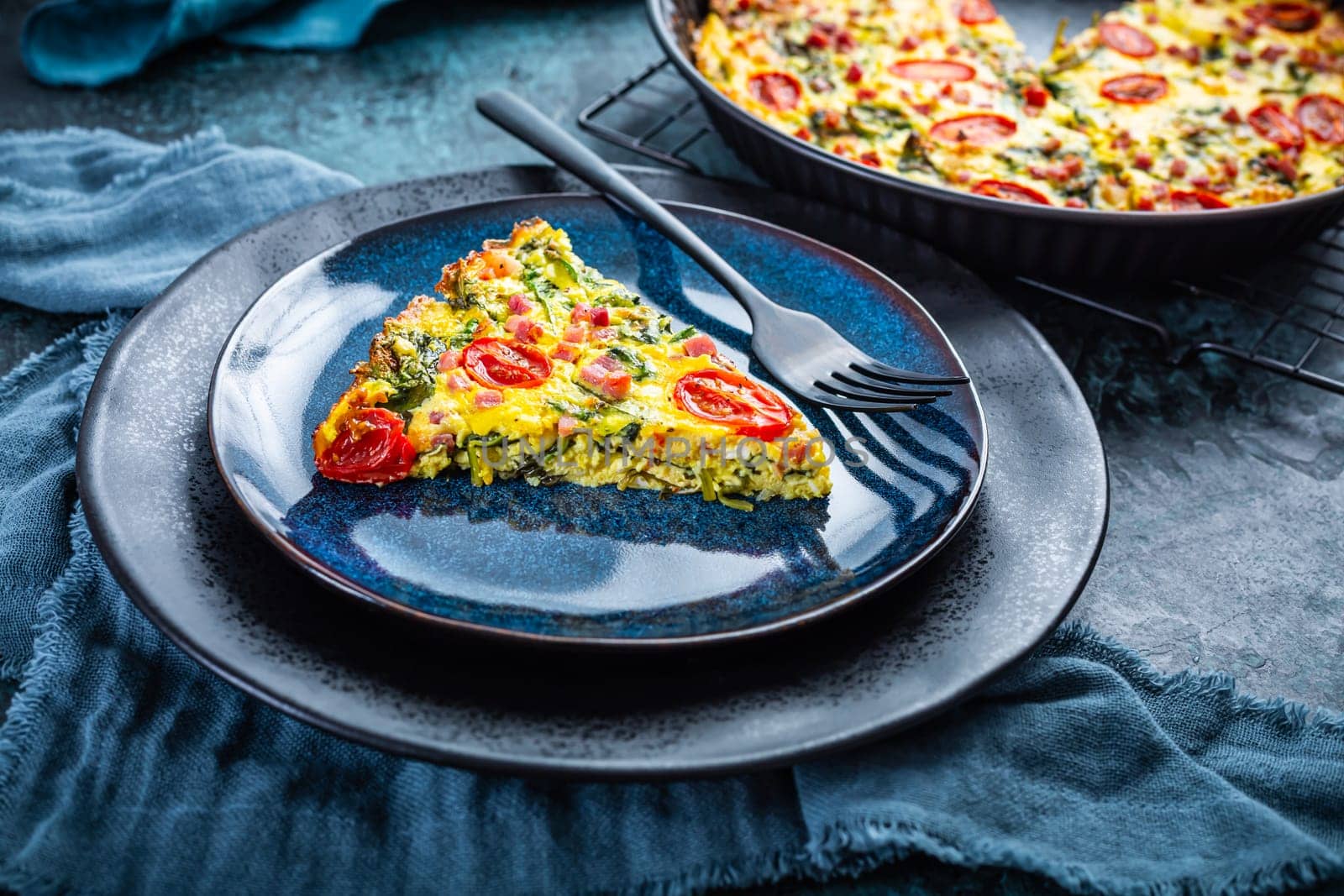 Homemade frittata with spinach, curd cheese, bacon, onion and green onions