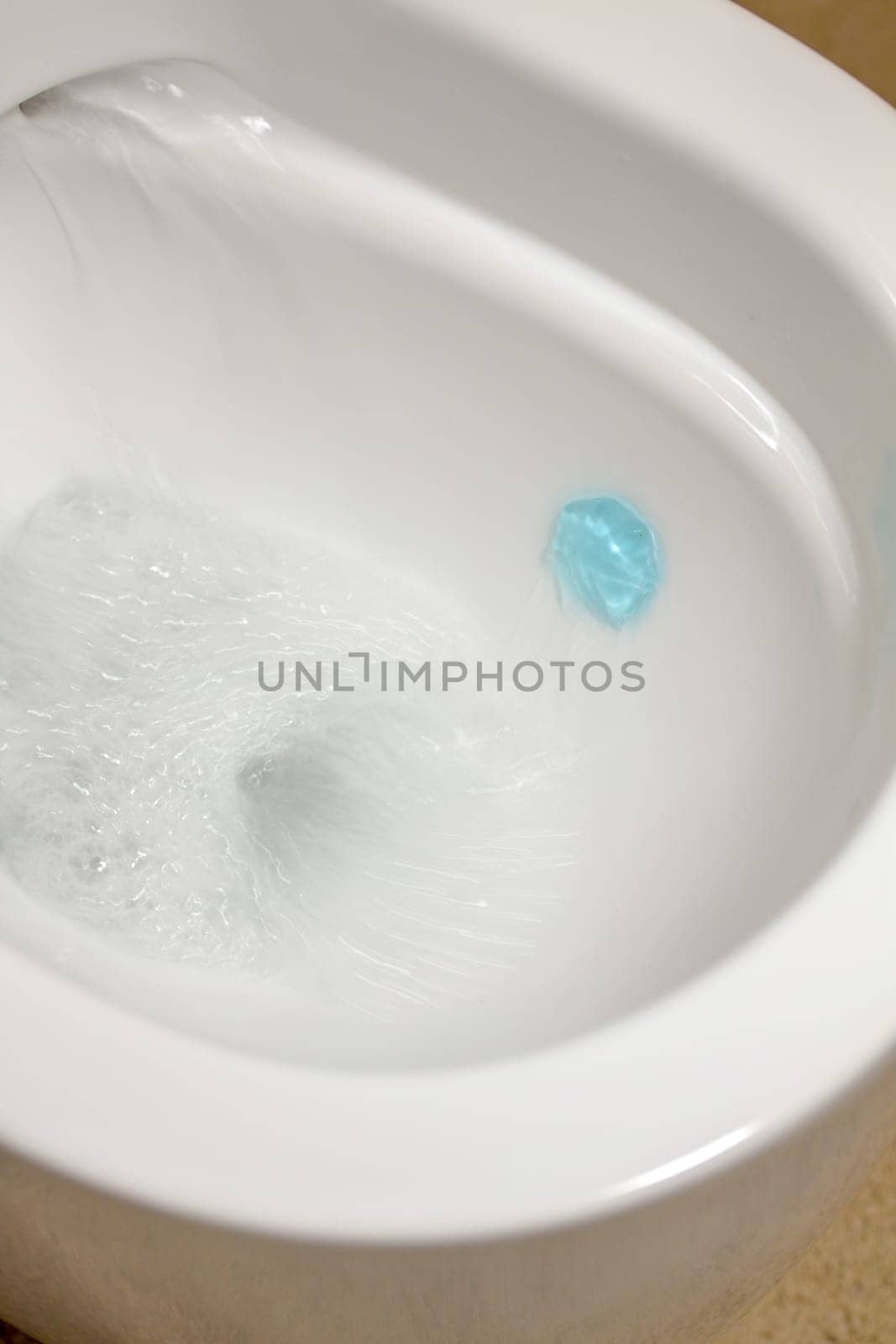 Modern toilet bowl with blue detergent for cleaning and disinfection