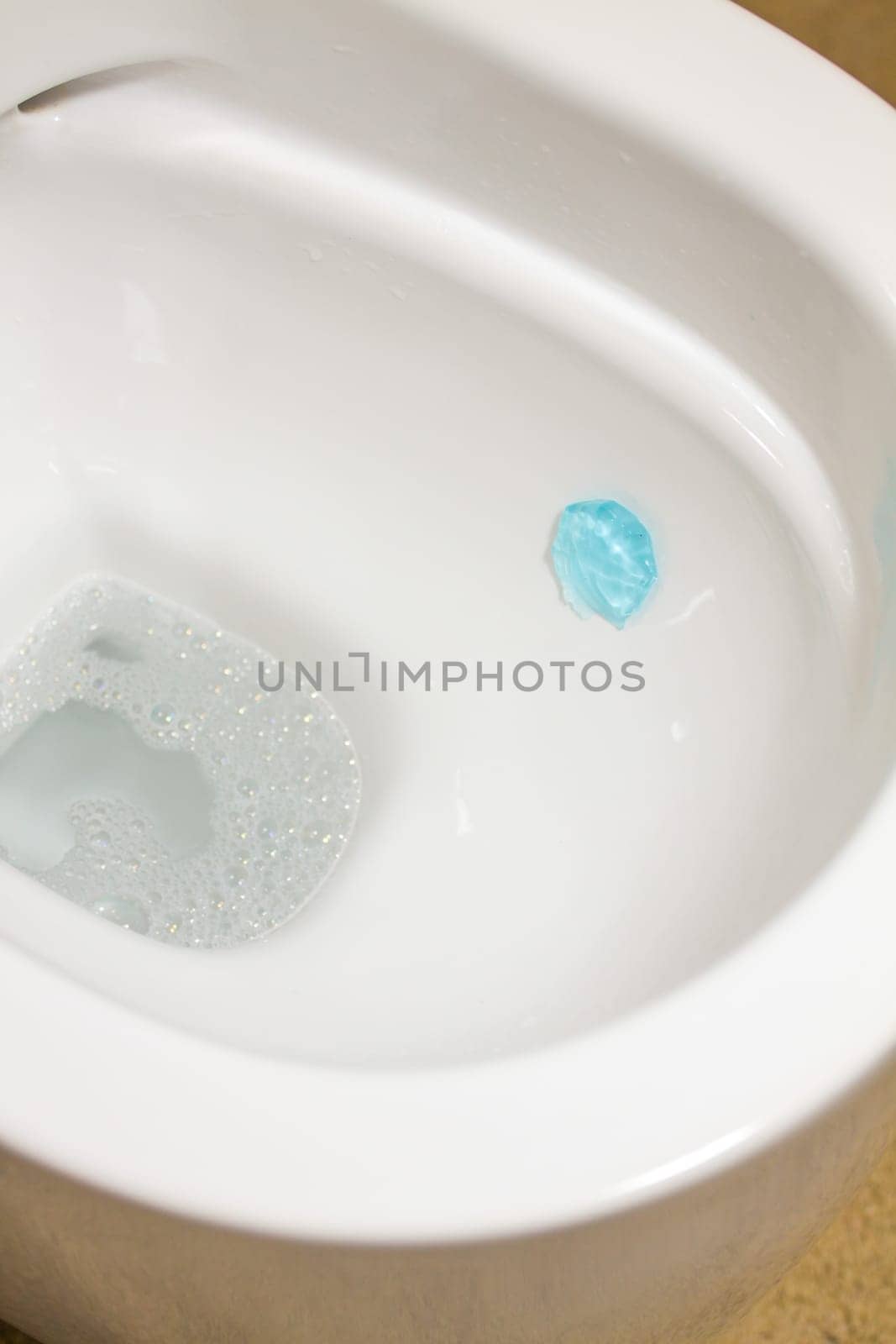 Modern toilet bowl with blue detergent for cleaning and disinfection