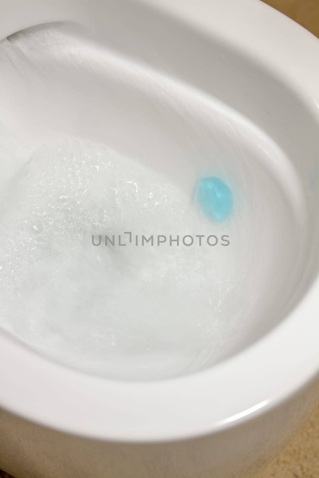 Modern toilet bowl with blue detergent for cleaning and disinfection