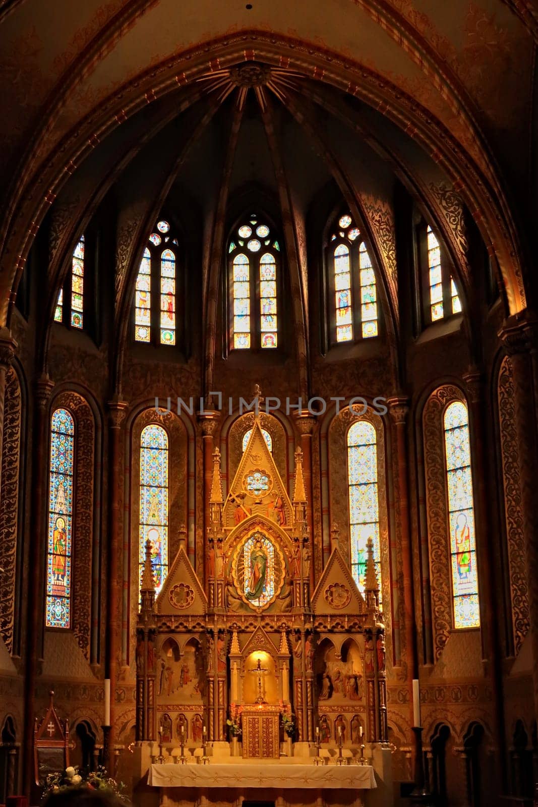Elaborate altar in front of stained glass windows in gothic style shape inside the Matthias Church, Budapest, Hungary 2022