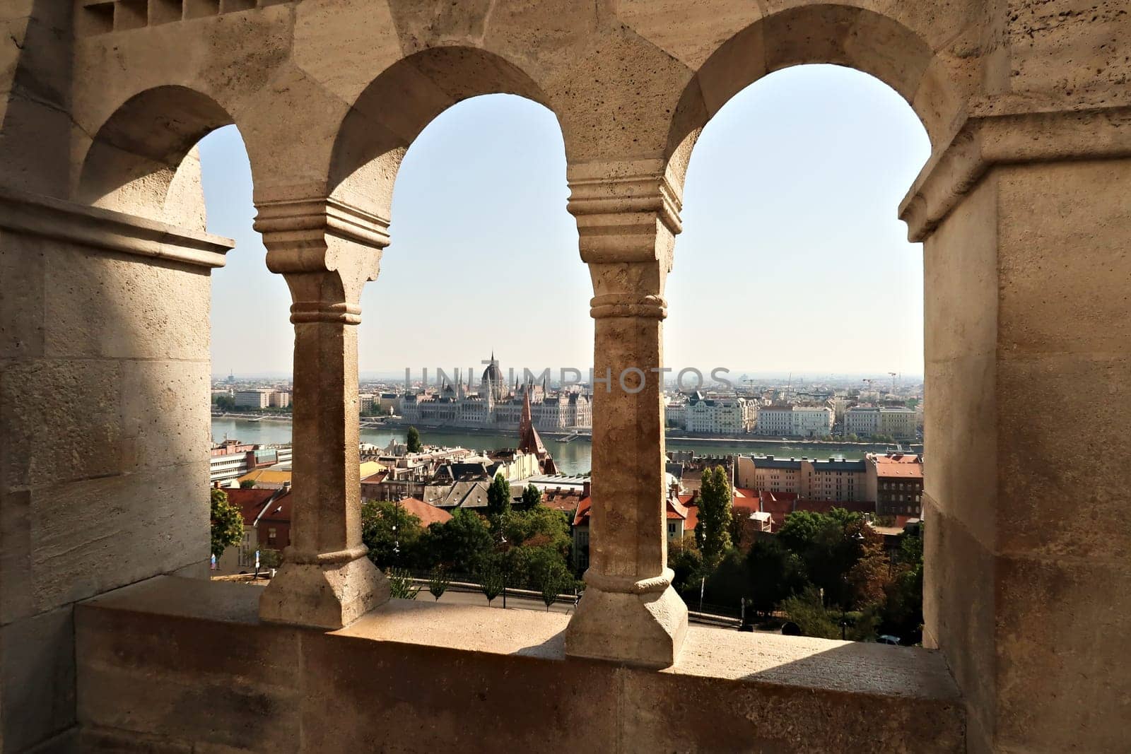 View through a stone window of the Fisherman's Bastion onto the Hungarian Parliament Building at the Danube River, Budapest, Hungary 2022