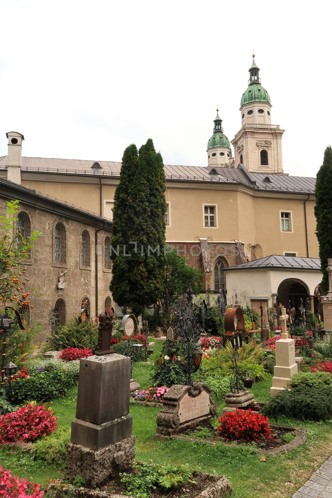 Graves on the St., Saint Peter's Cemetery, Petersfriedhof in front of two bell towers, clock towers of the St. Peter's Abbey, Monastery, Stift Sankt Peter, Salzburg, Austria 2022