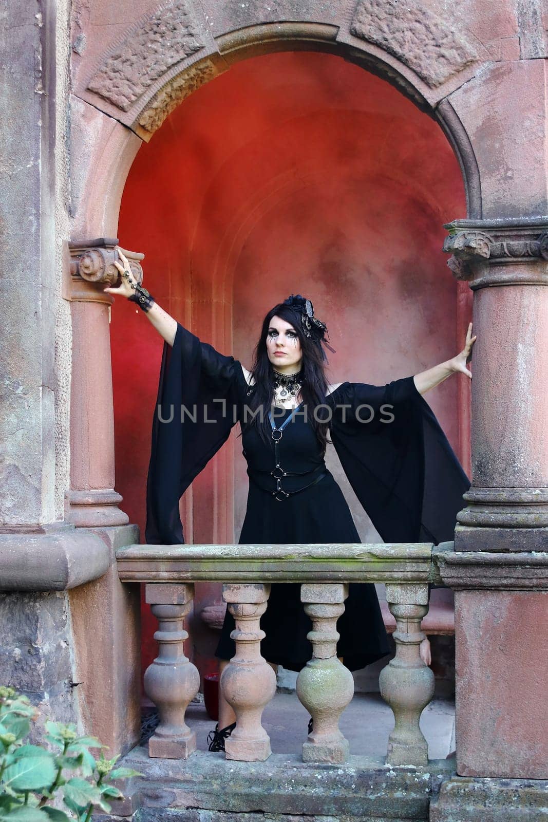 A woman dressed as a witch in an archway with red smoke