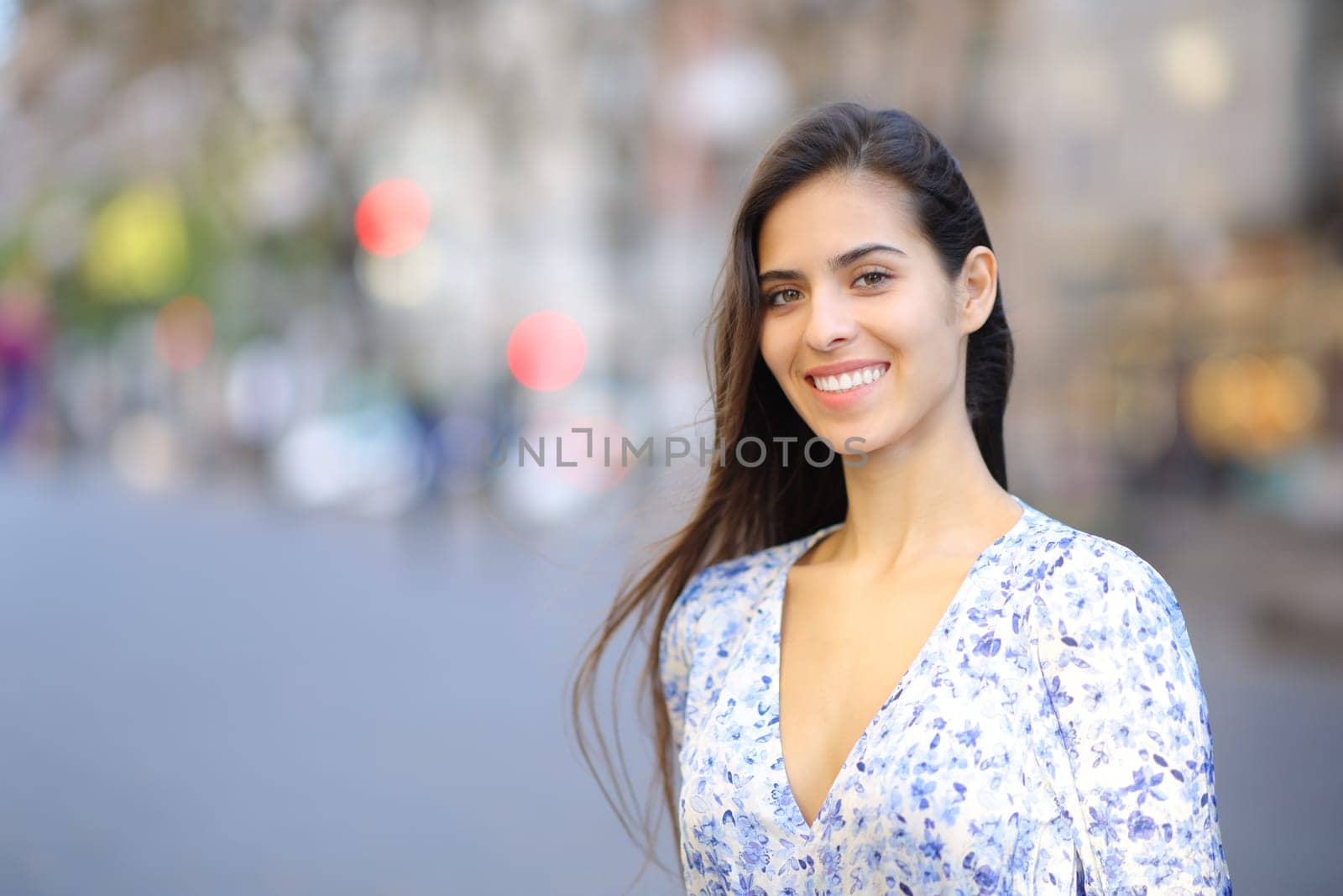 Happy woman looking at camera with perfect smile standing in the street