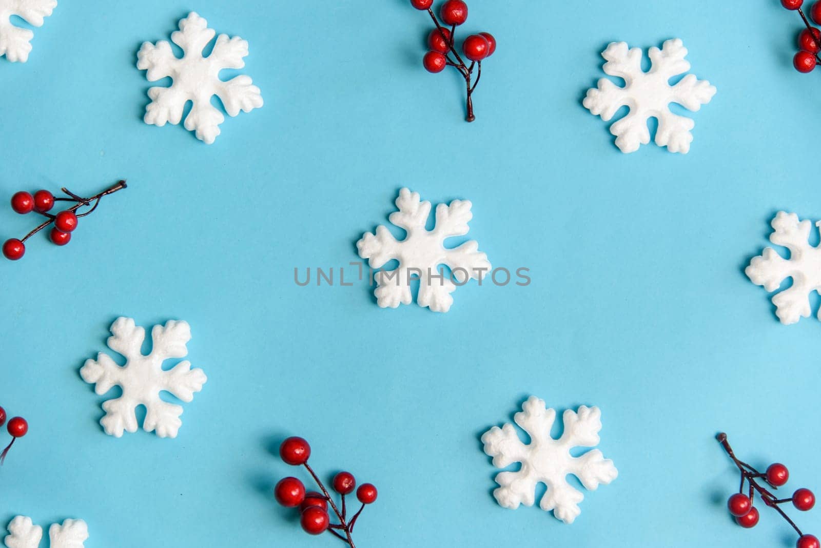 Minimal christmas, new year and winter holiday composition. Flat lay. Creative pattern banner with snow flakes nad red berries on pastel blue background. Christmas and wintertime concept. Top view.