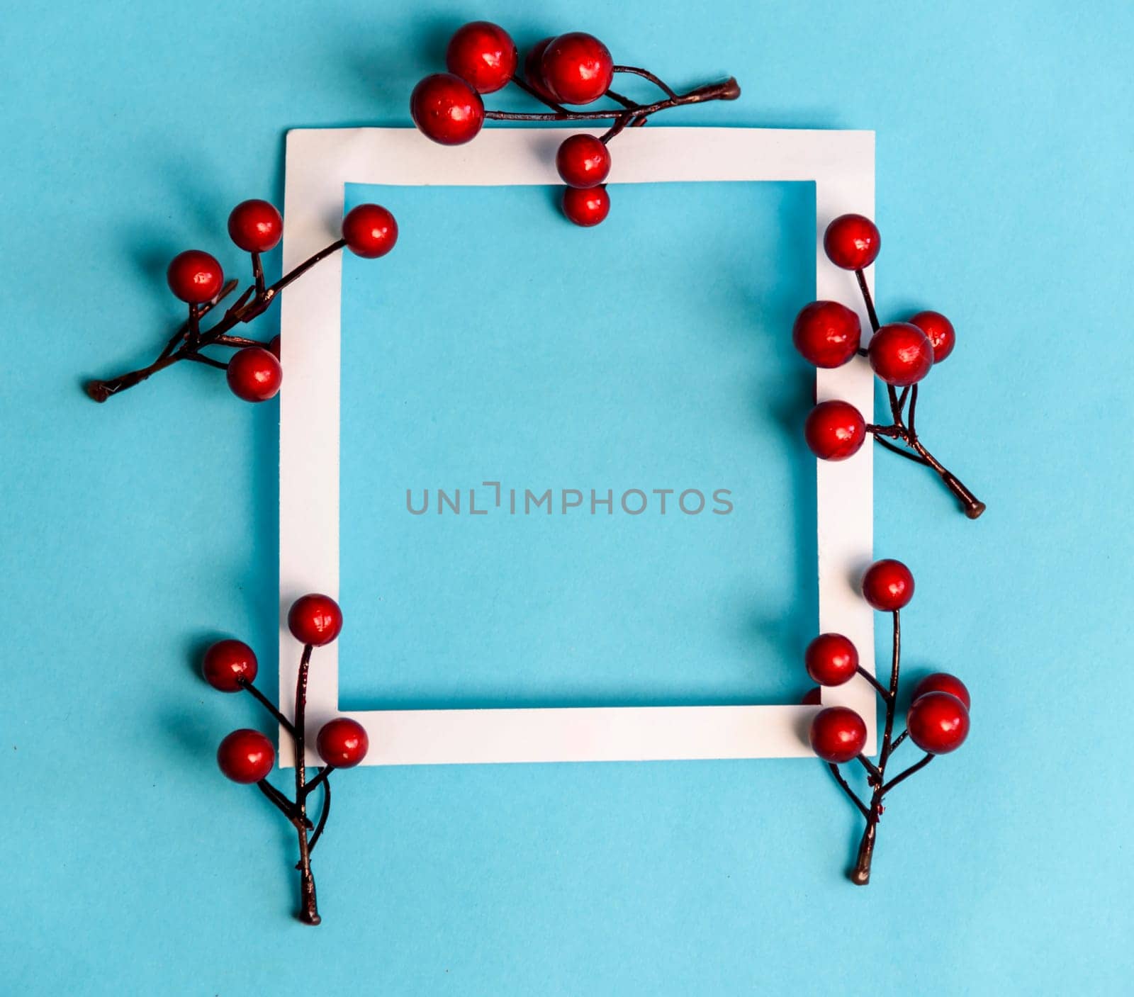 Christmas and new year background composition. Empty photo frame with christmas decoration on pastel blue paper. Minimal winter holiday concept. Flat lay.