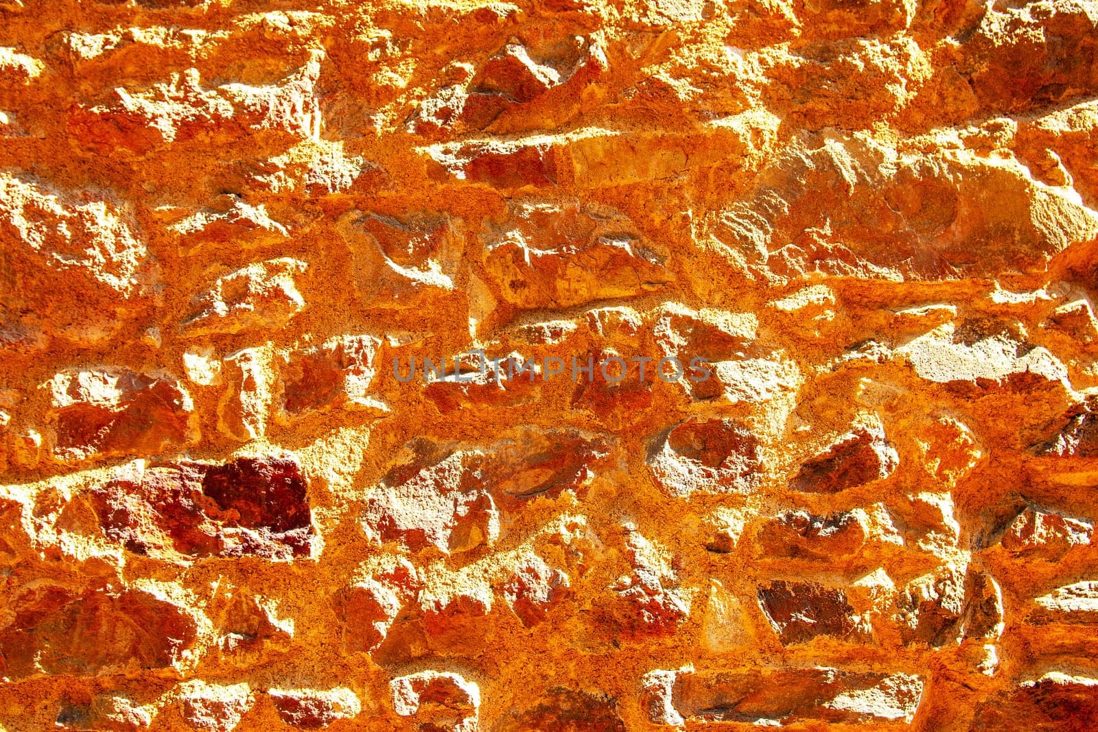 Brown yellow texture of a concrete wall. Closeup of brown  background of a concrete wall with a hilly uneven surface on a sunny day. Abstract backdrop.