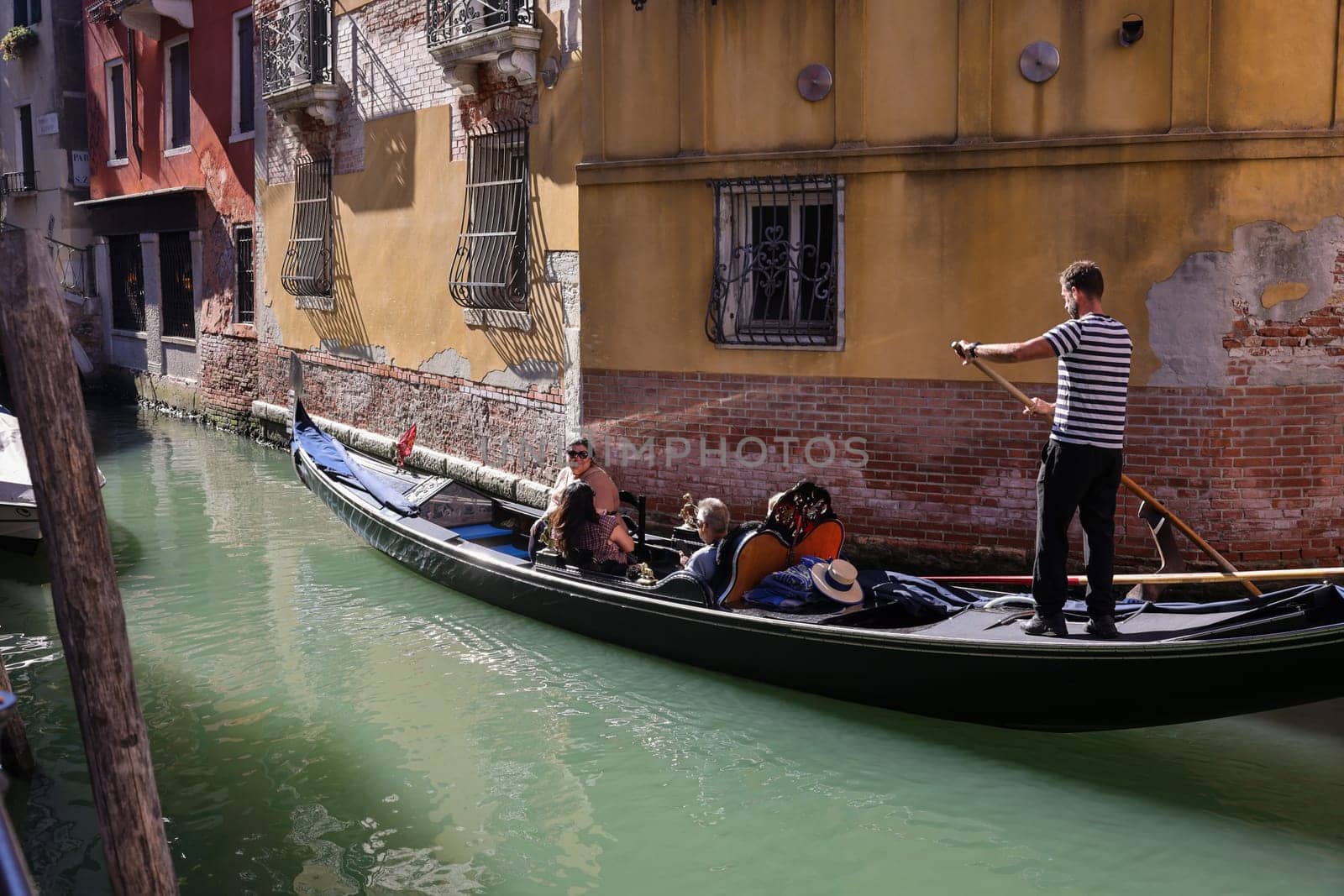 Venice, Italy - September 5, 2022: One of the most recognizable tourist attractions in the world - a gondola cruise through the narrow canals in Venice