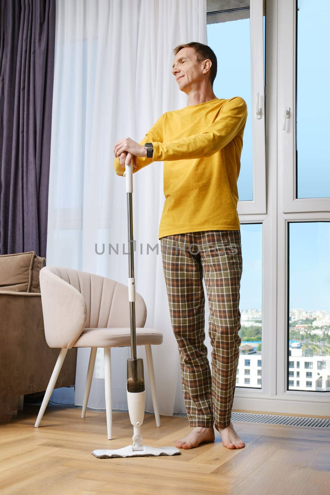 Middle aged man is pleased with himself after doing house cleaning