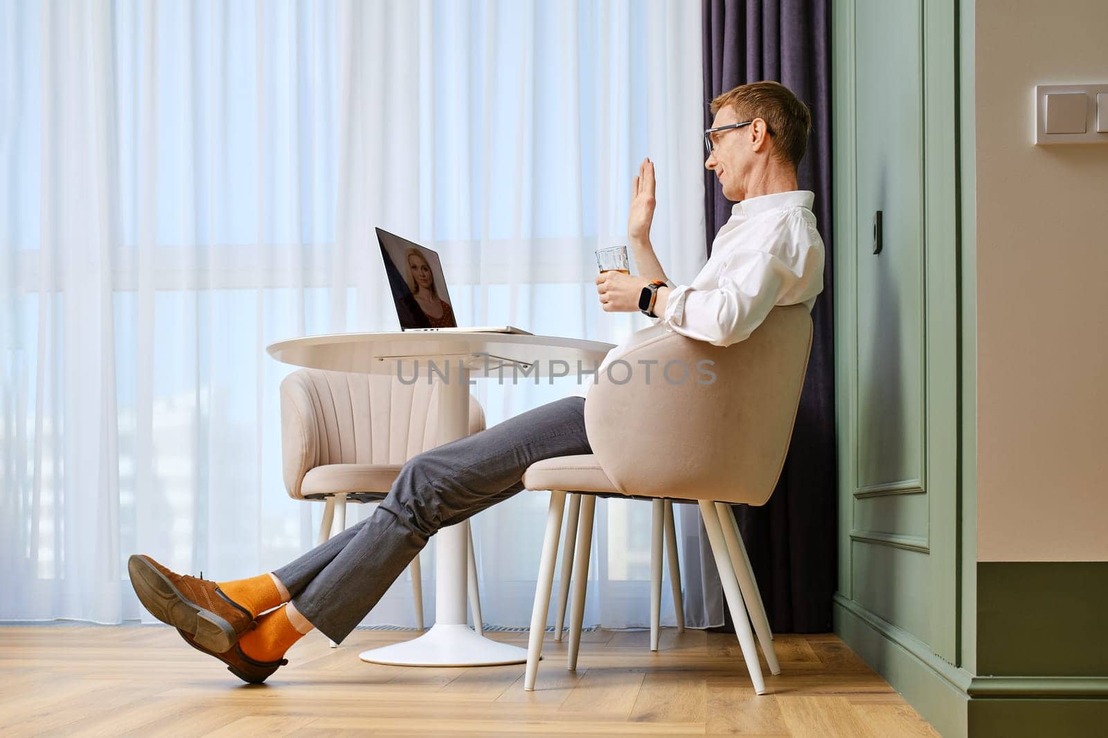 Positive middle aged man makes video call on laptop
