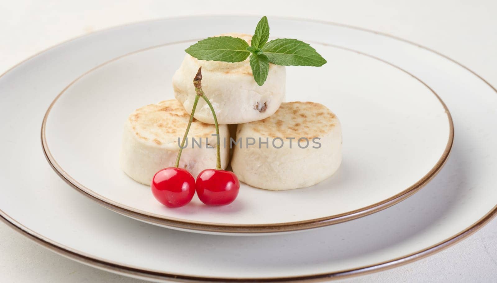 Round small fried cheesecakes on a plate with blueberries. Background white