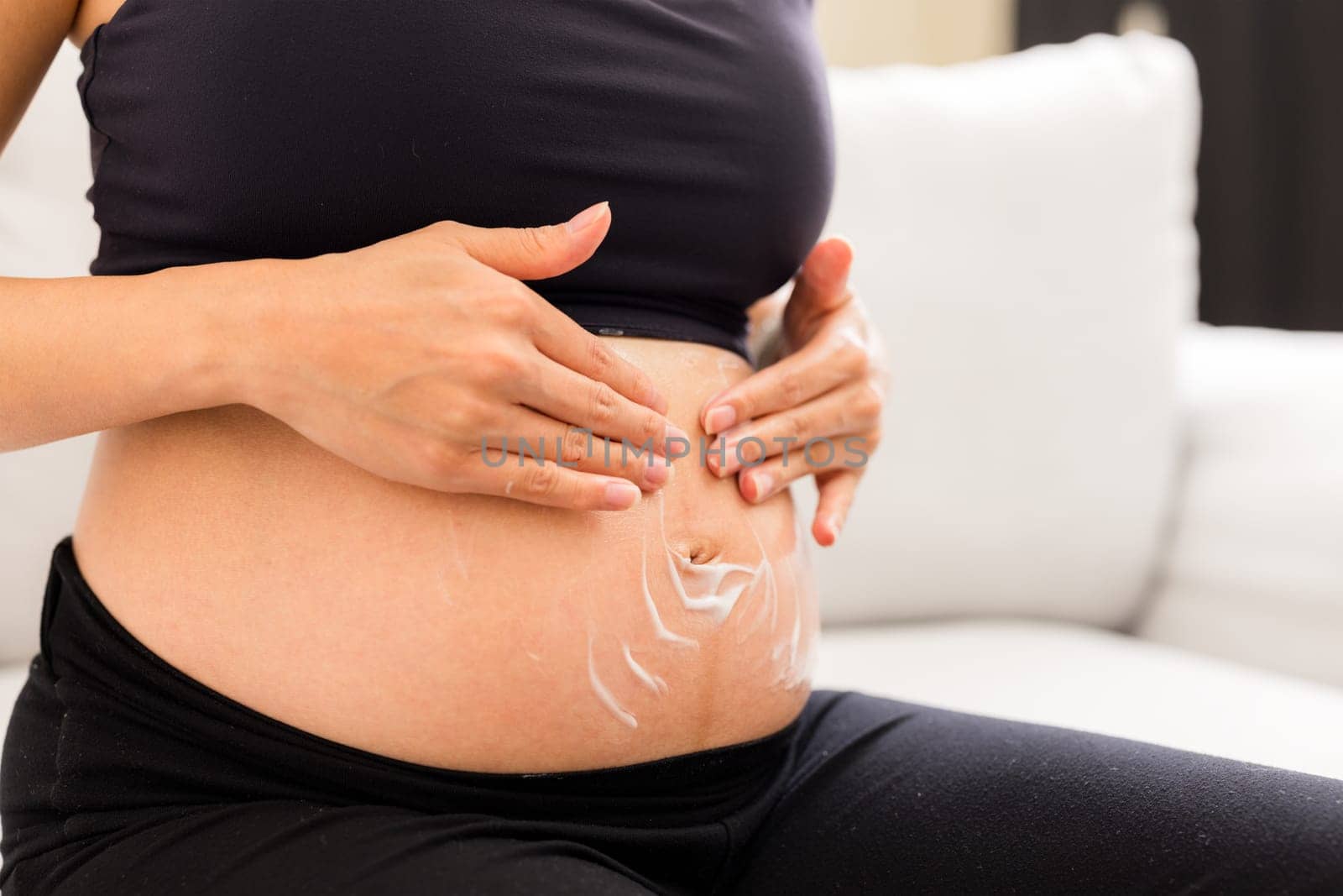 Pregnant woman putting cream on her belly to avoid stretch mark