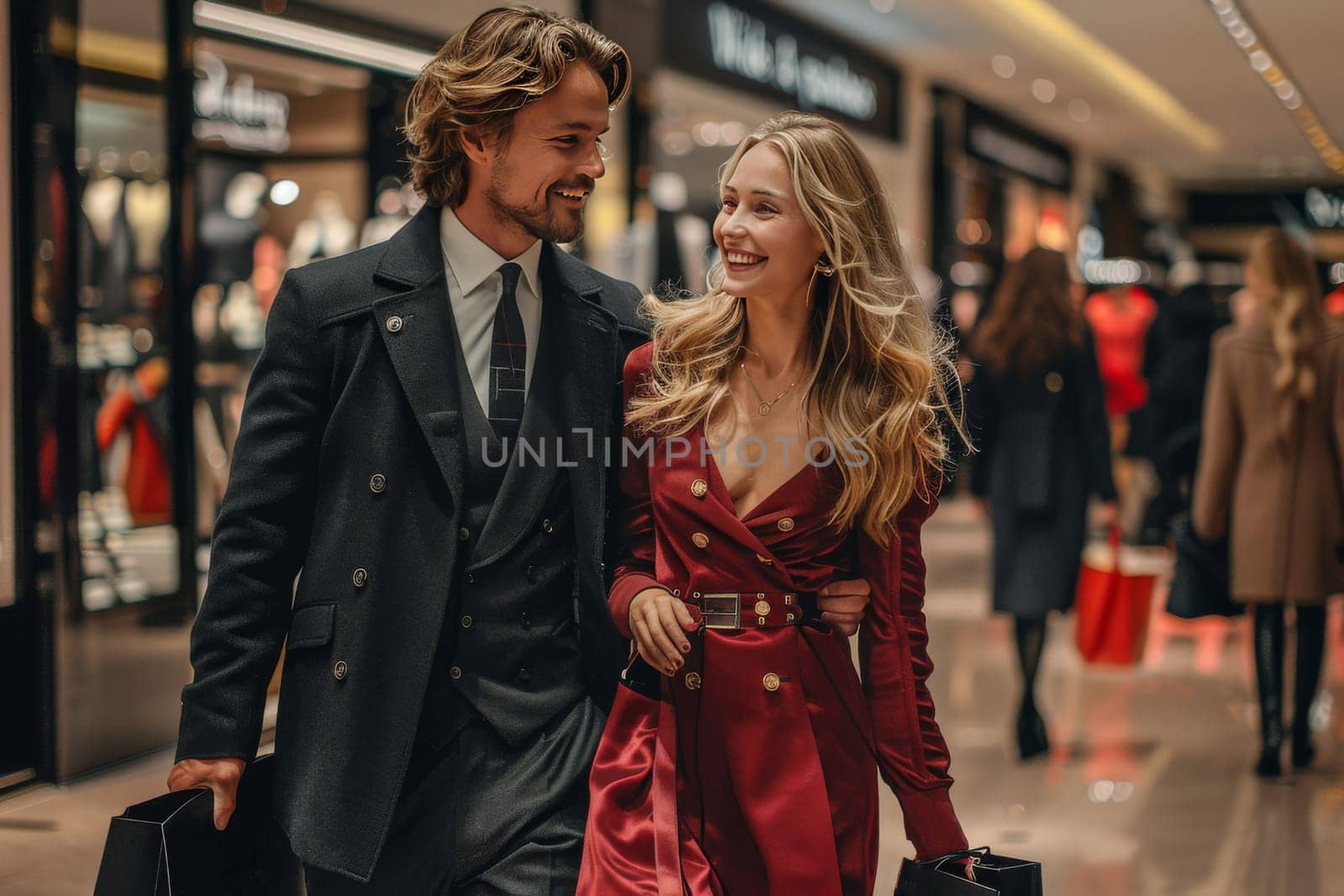 A man in his thirties donning a black suit and a woman, presumably a love couple, leisurely walking through a busy mall lined with various stores and shoppers.