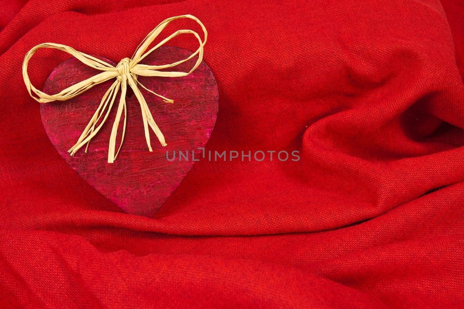 Wooden red heart on red cloth as a symbol of love