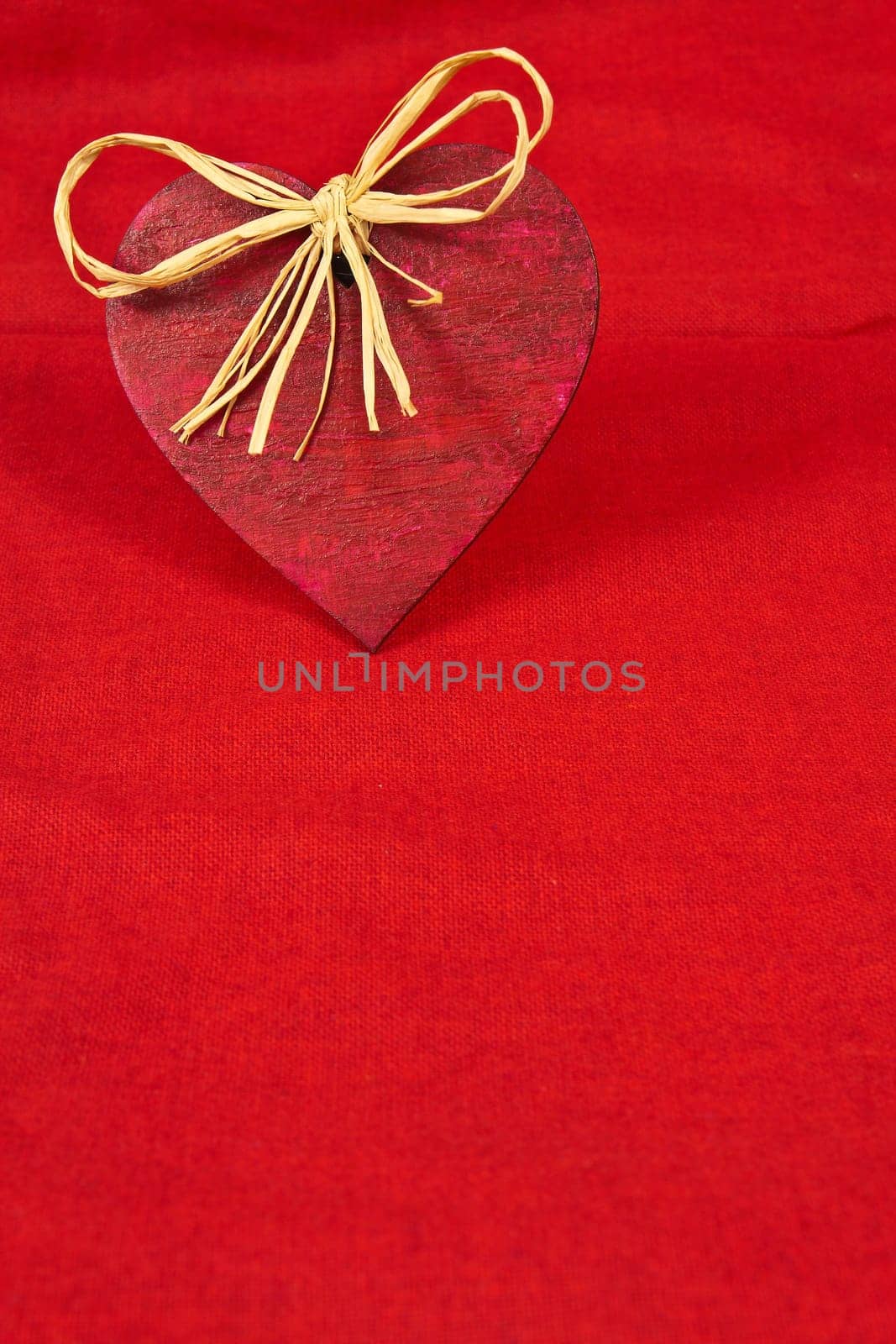 Wooden red heart on red cloth as a symbol of love