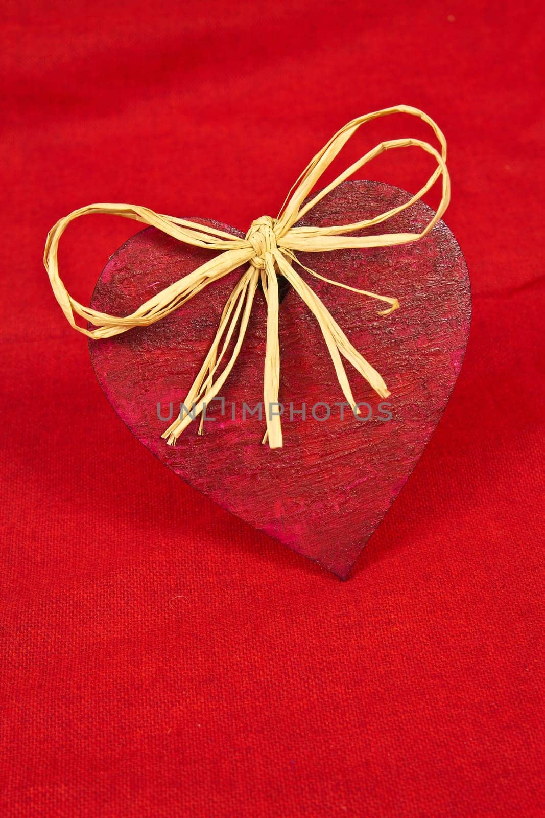 Wooden red heart on red cloth as a symbol of love