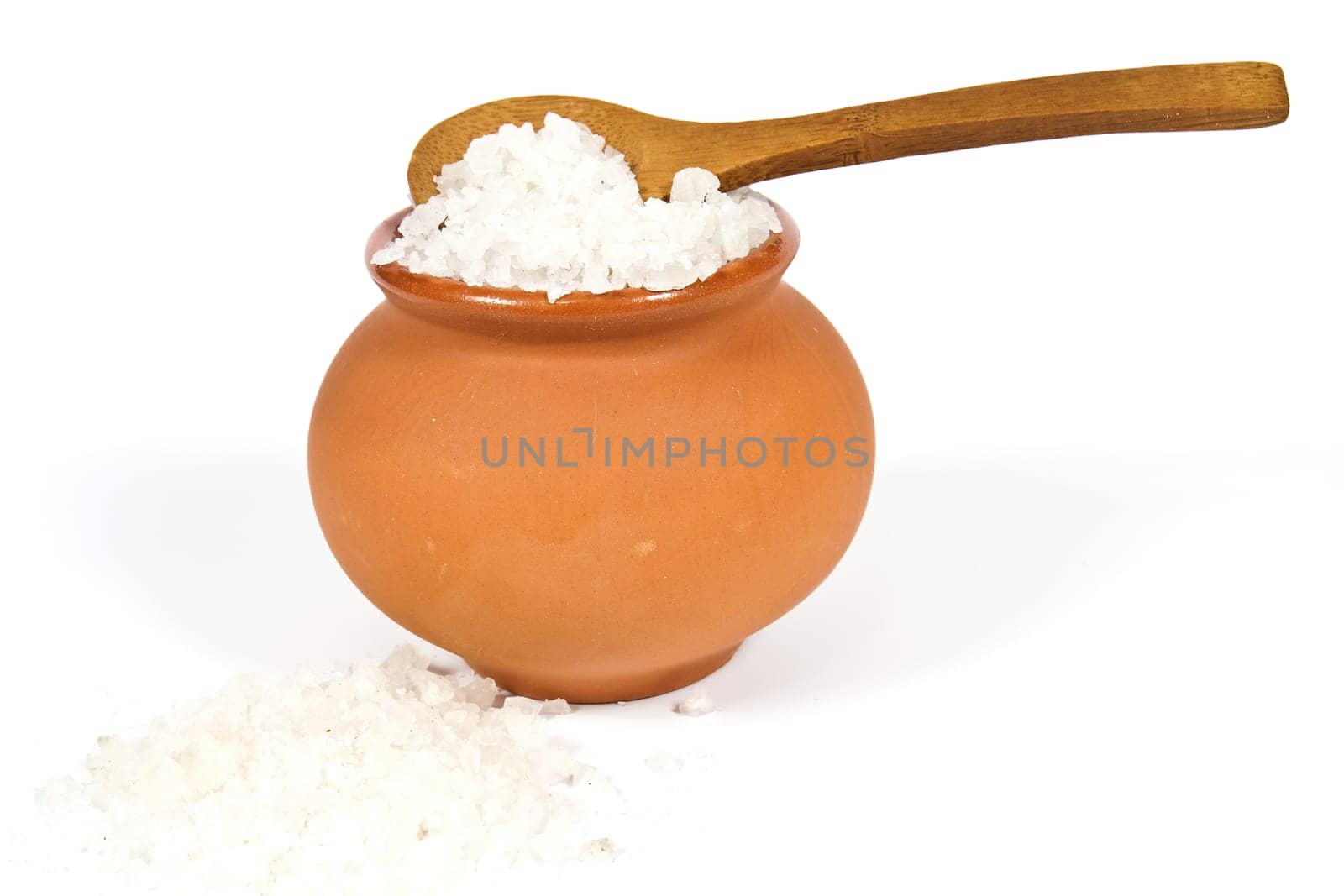 Sea salt crystals in clay pot with a wooden spoon