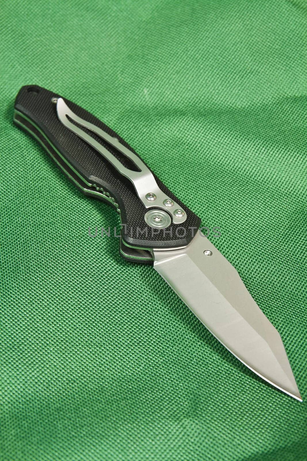 Folding knife with a black handle and lock on green canvas