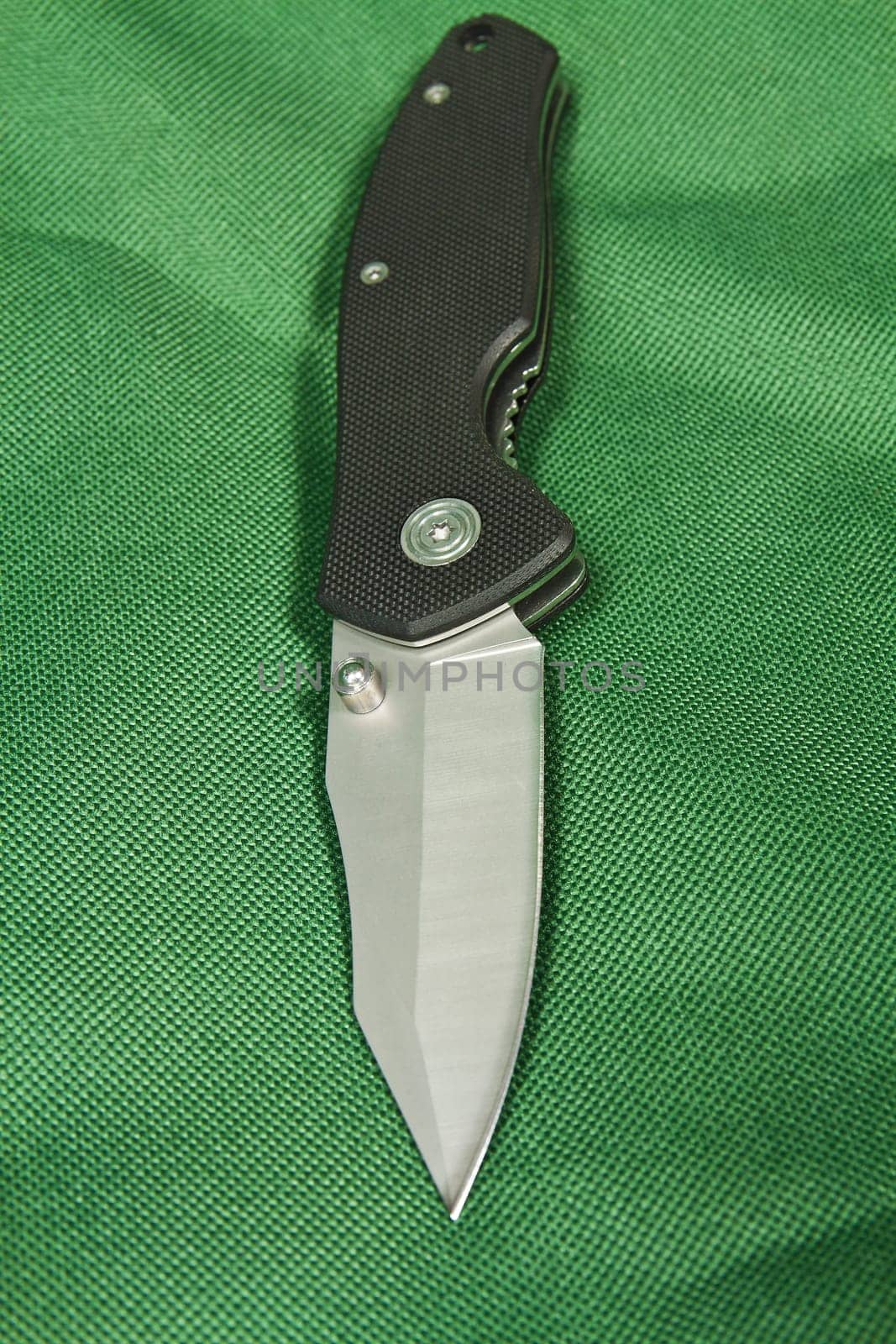 Folding knife with a black handle and lock on green canvas