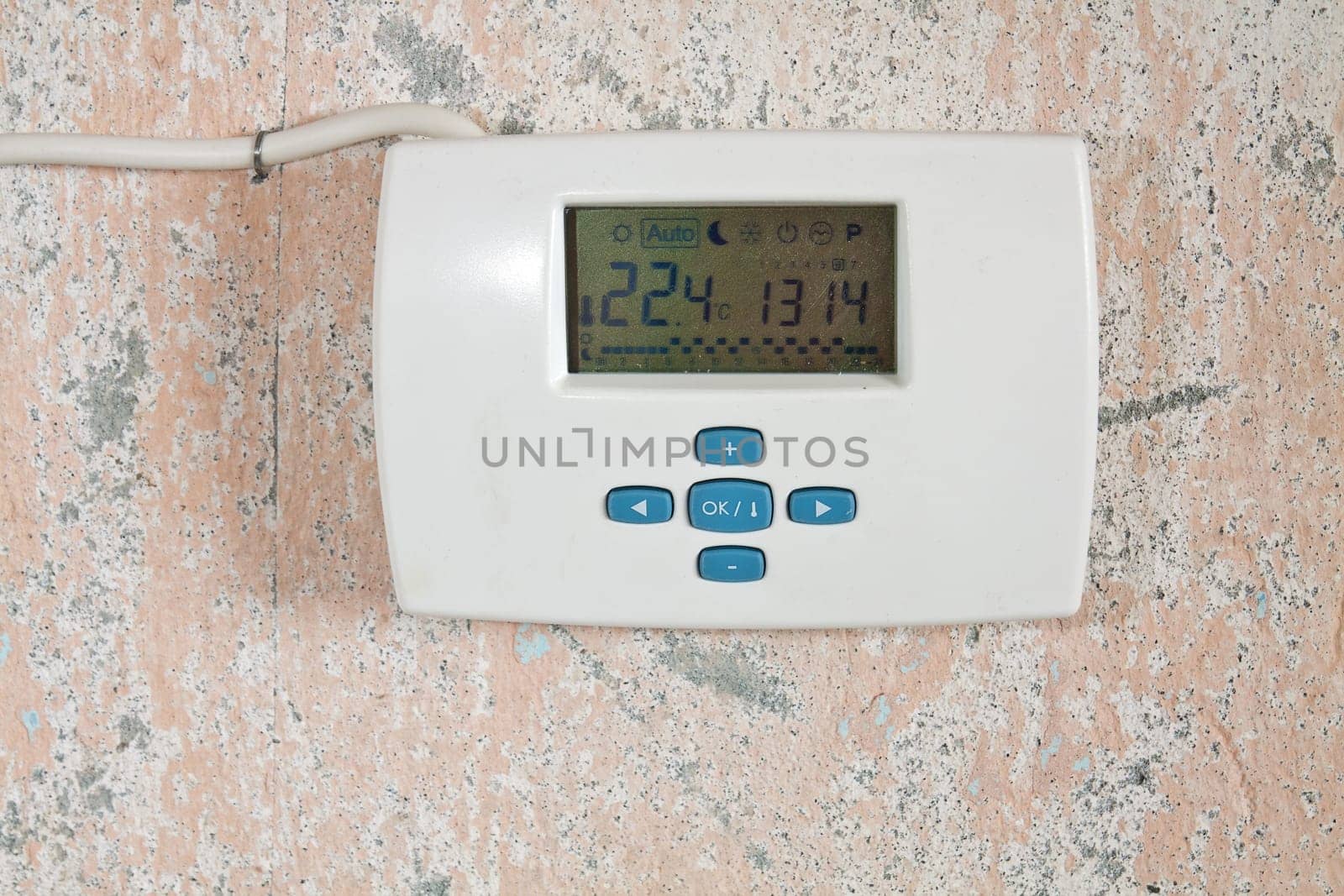 Electronic weekly programmer mounted on a wall with peeling paint