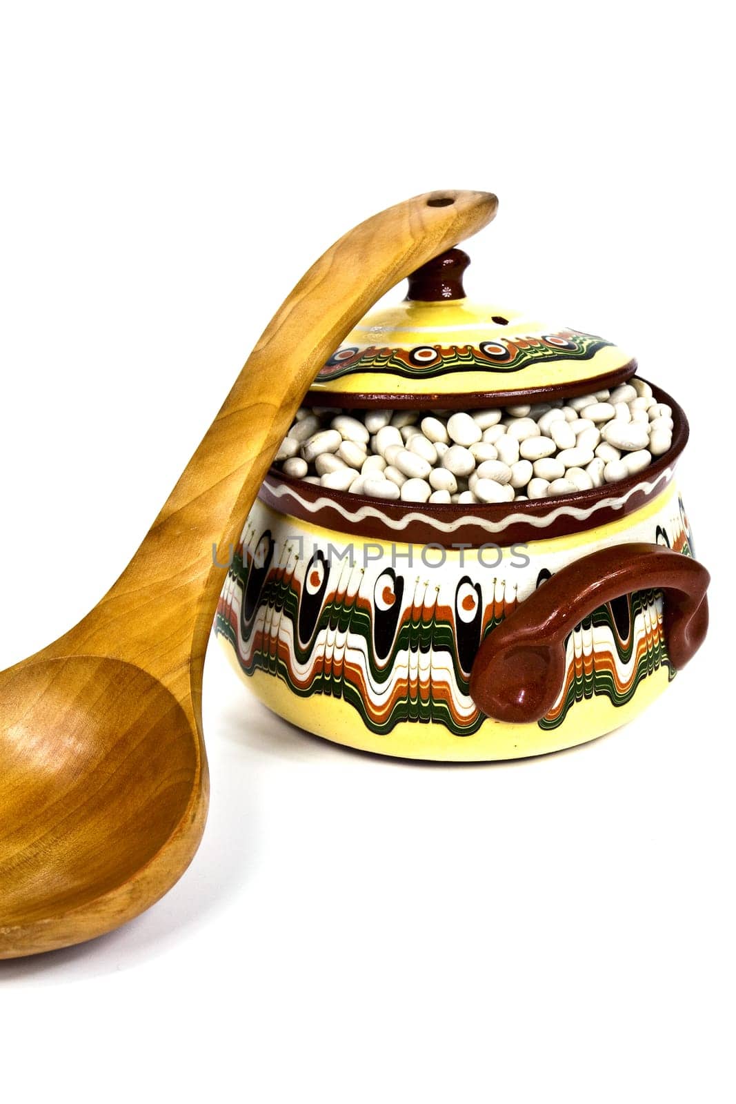 Supported on wooden spoon colored ceramic pot on a white background