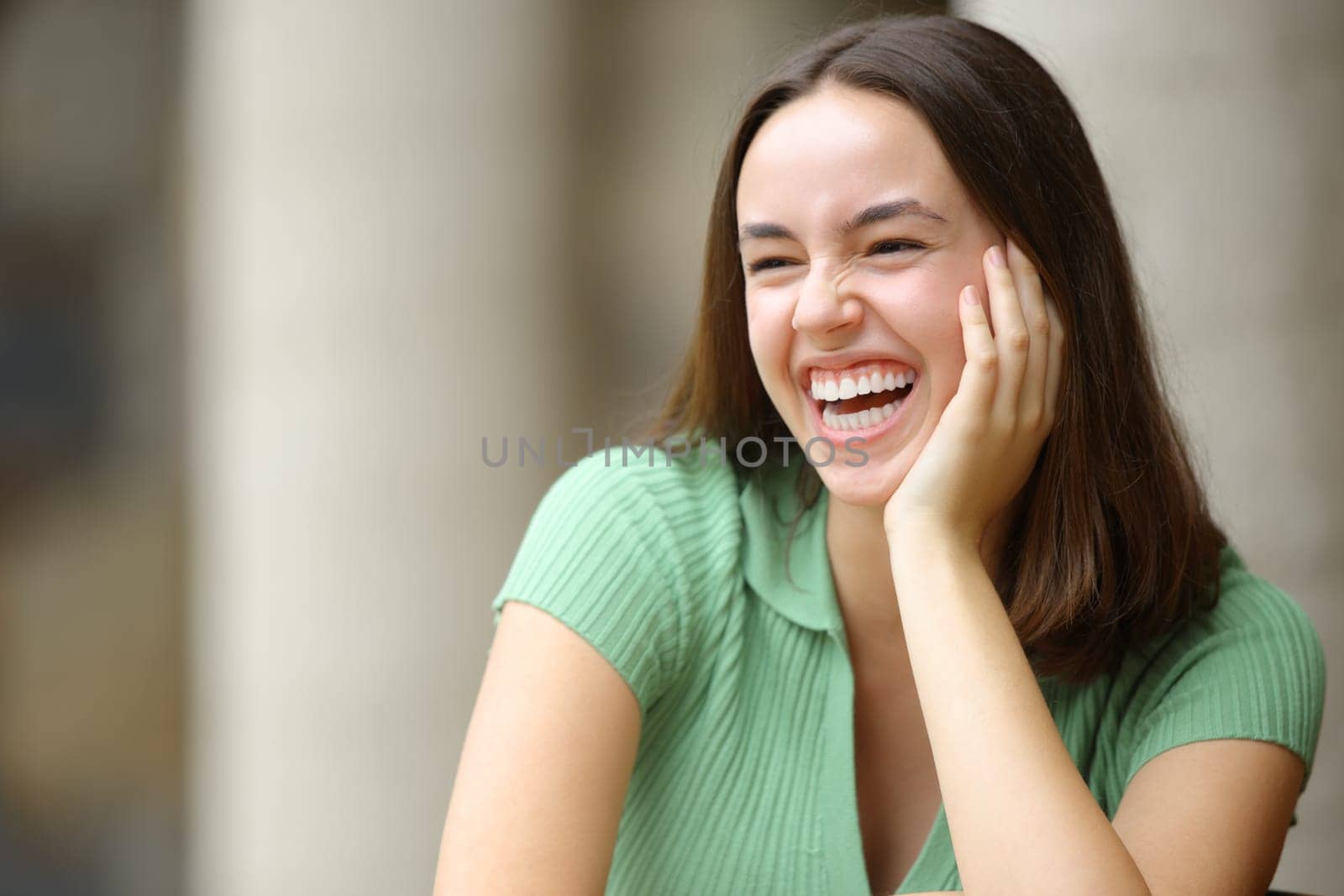 Happy woman laughing in the street with perfect white teeth looking away