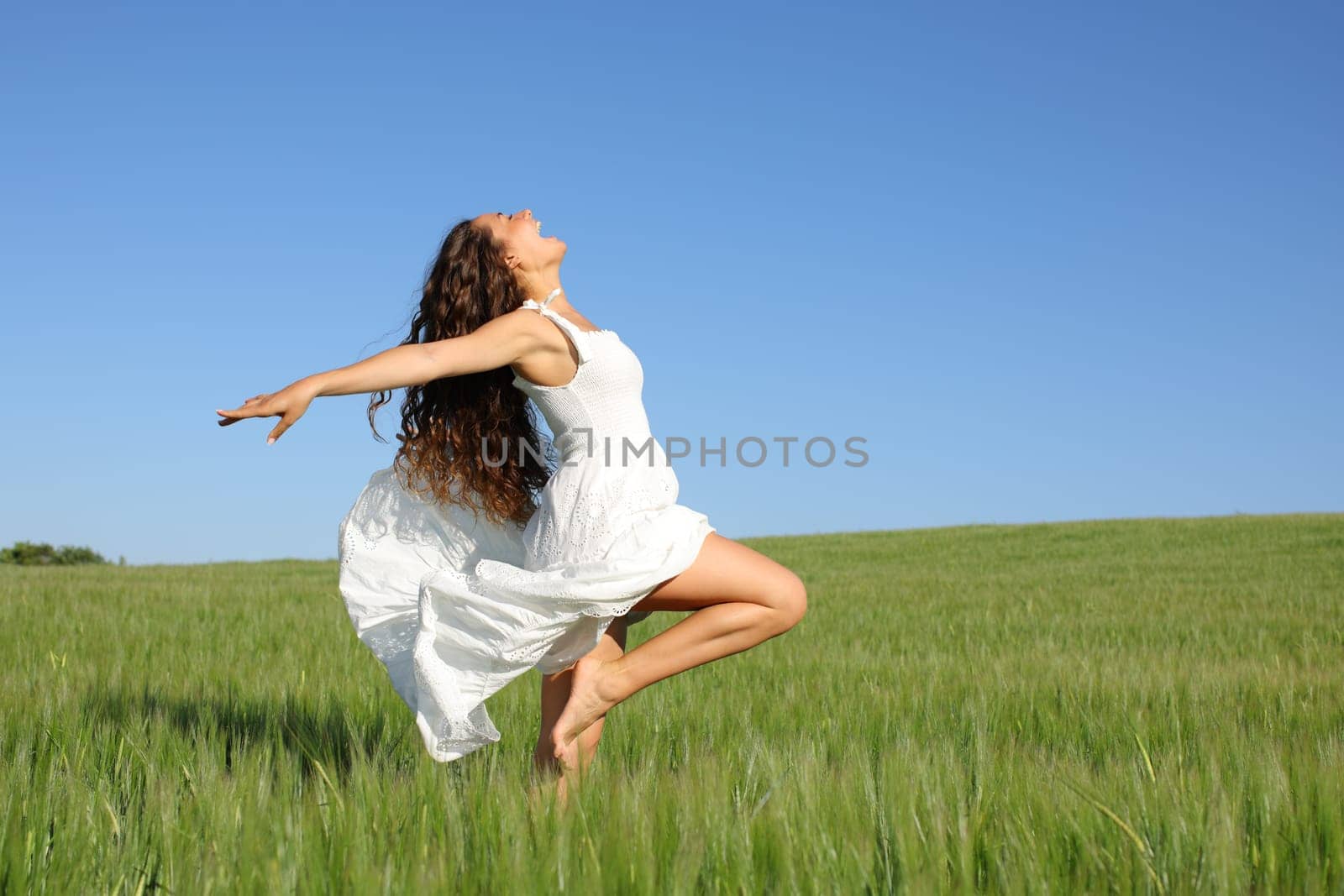 Profile of a woman with white dress posing screaming in a field