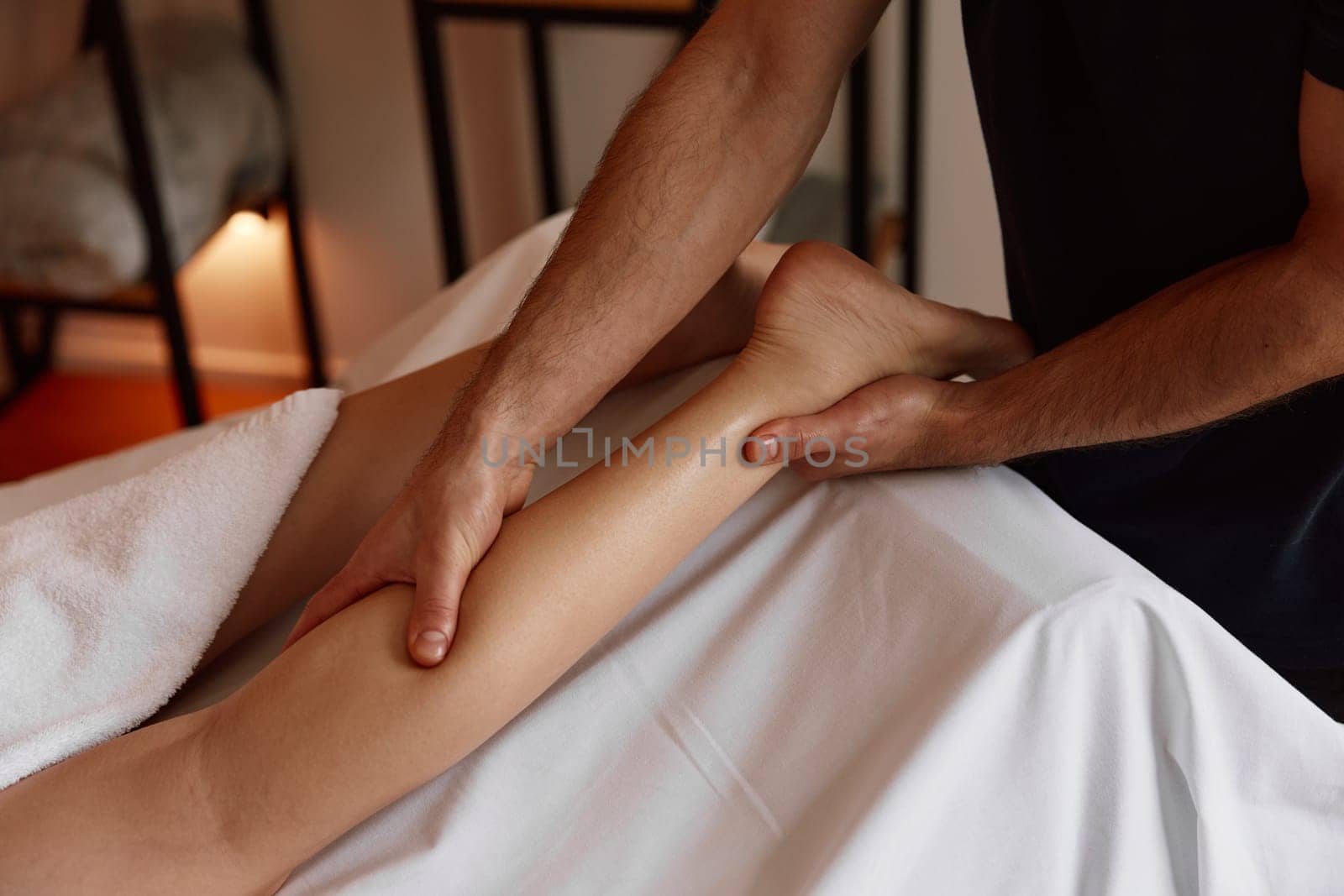 Crop of therapist massaging female leg in spa salon healing cramp muscle pain. Cosmetology and body treatment procedure