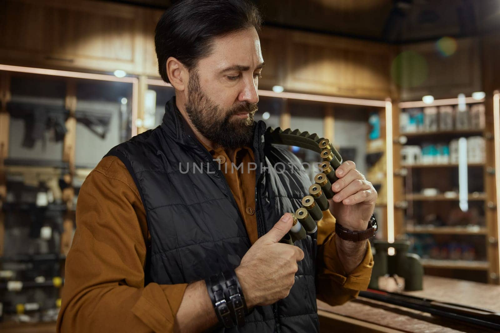 Hunter weapon shop with military arsenal assortment concept. Salesman or buyer hands holding belt with bullets closeup
