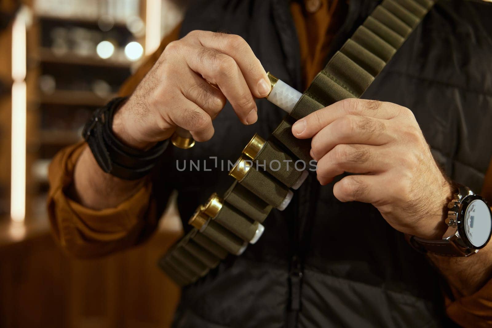 Hunter hands placing bullets into the ammo belt. Hunter weapon shop with military arsenal assortment concept