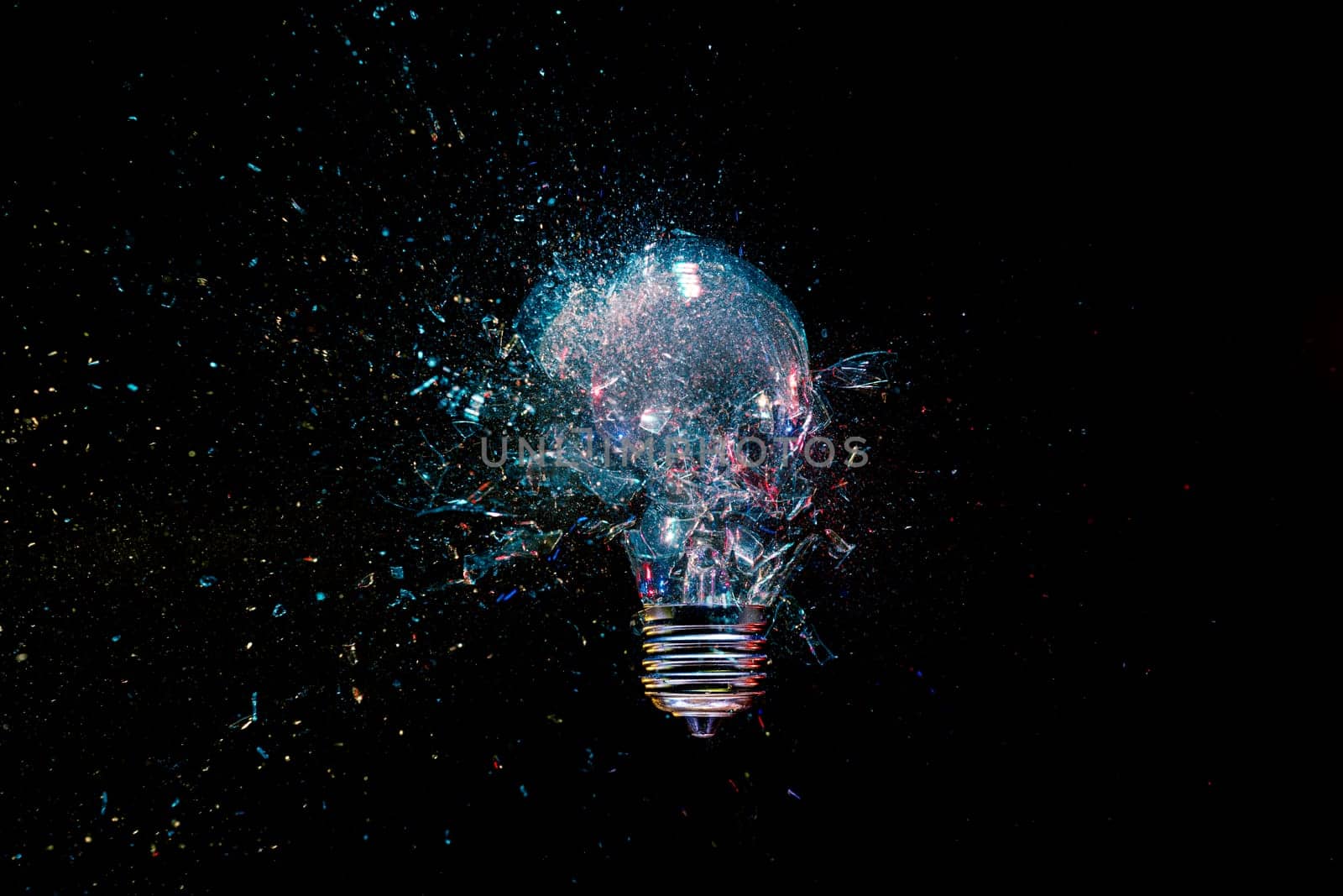 High-speed lightbulb exploding  glass shattering black background