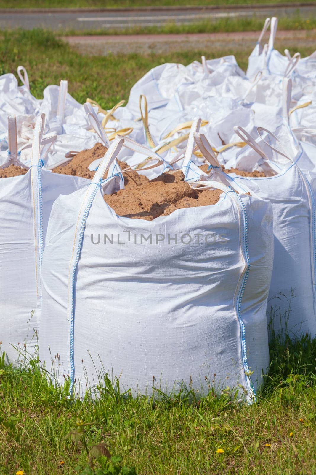 White garbage bags with construction waste standing on a meadow, Germany