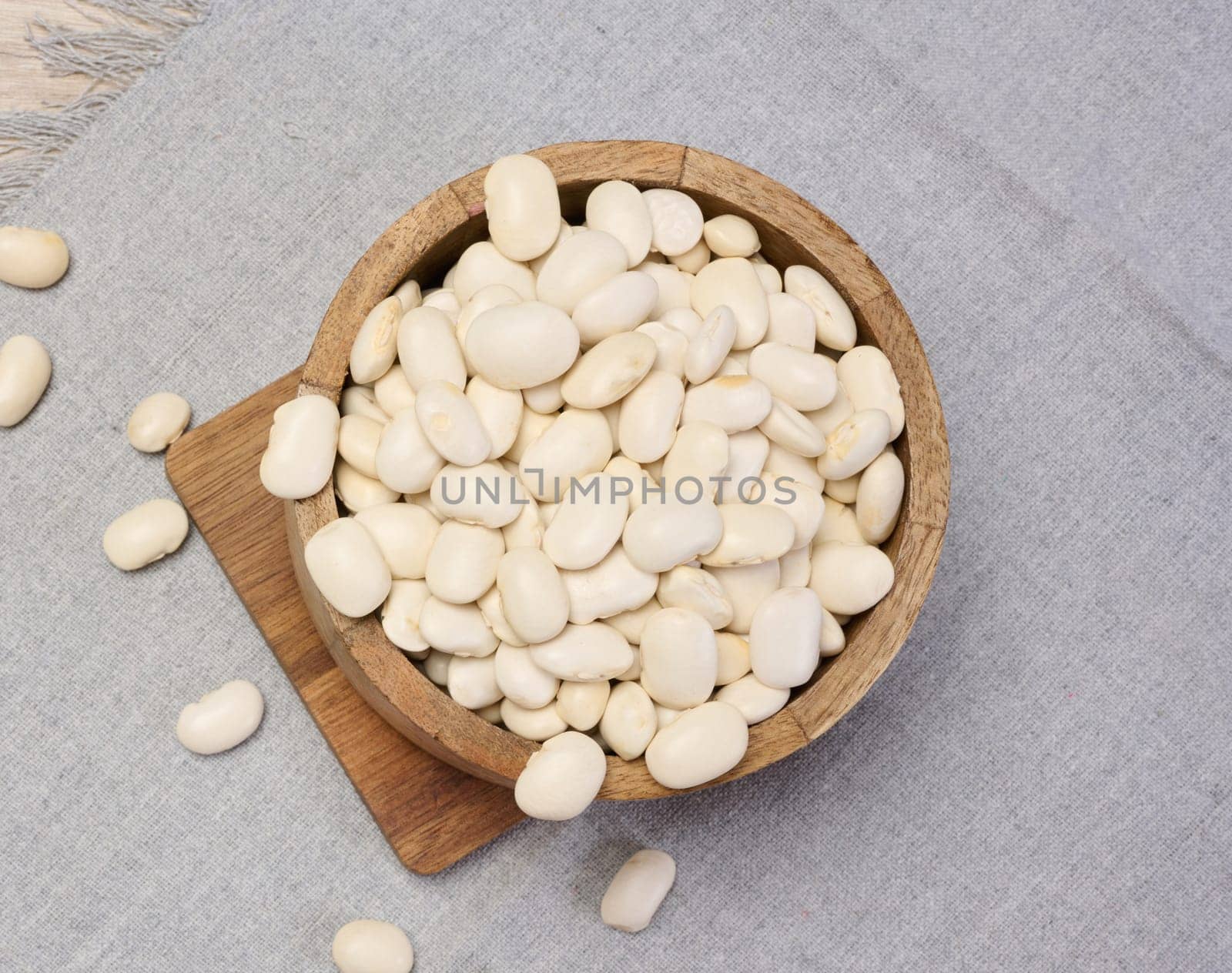 Raw white beans in a plate on the table, top view