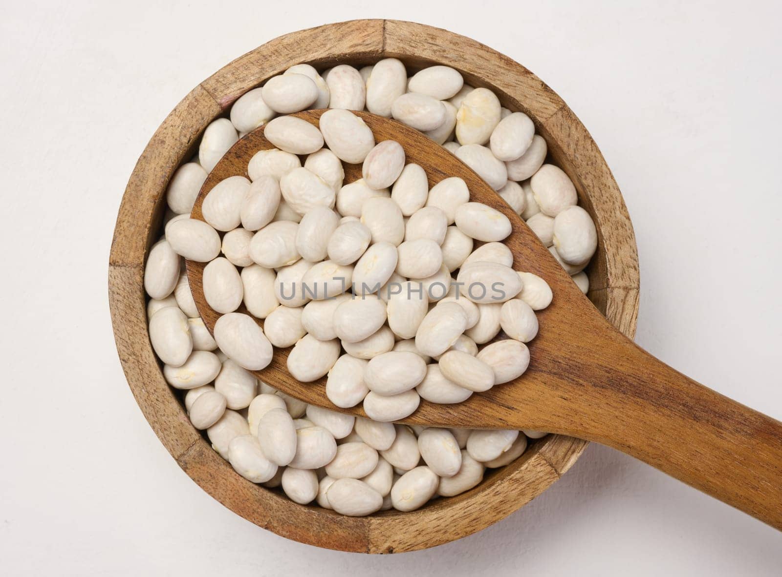 Raw white beans in a plate on the table, top view.