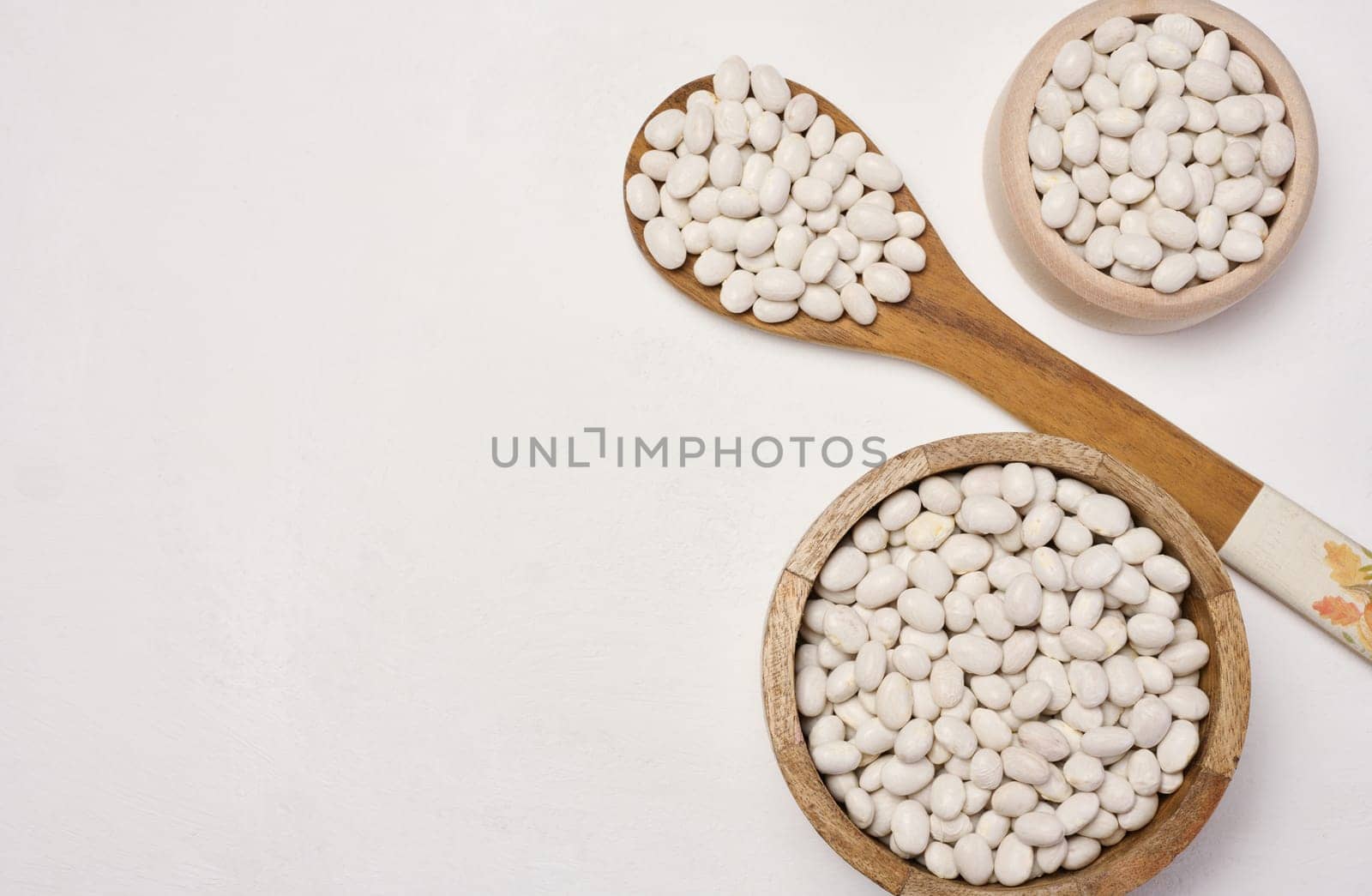 Raw white beans in a plate on the table, top view. Copy space