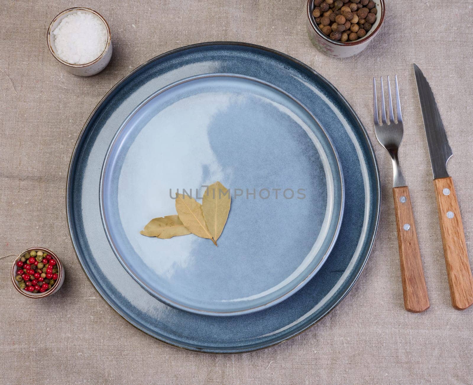 Empty round ceramic plate on the table with spices, top view