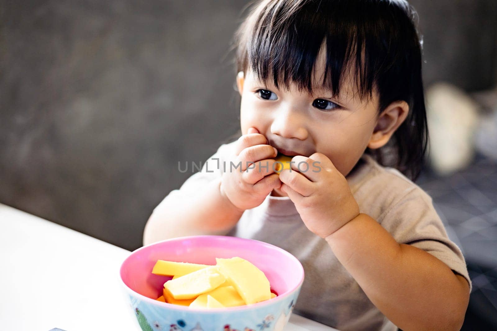 Cute boy eating mango at home. Asian child with healthy nutrition.