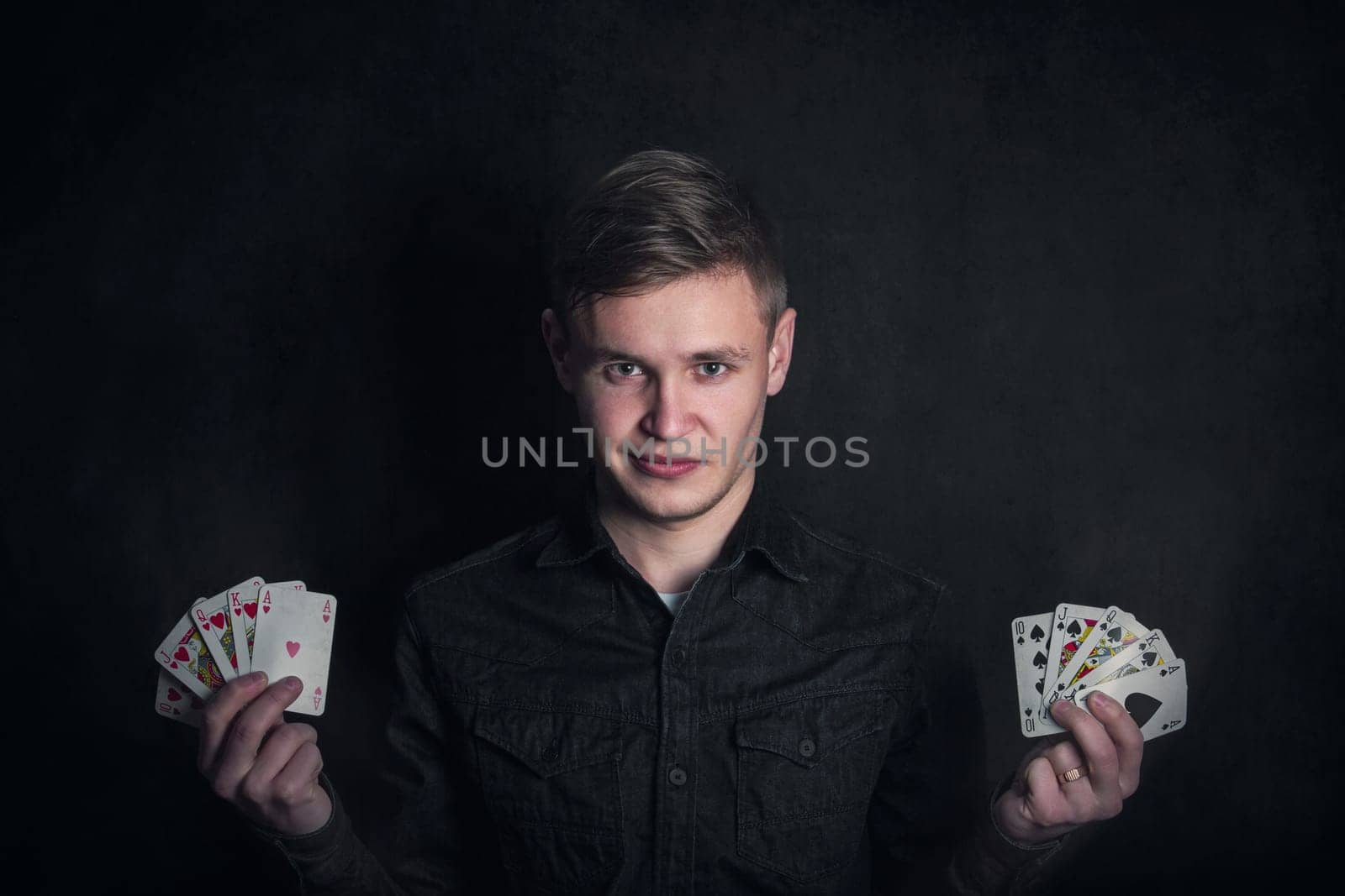 Gambler holding playing cards in both hands. Royal flush successful poker combinations. Casino games tournament advertisement. Lucky gamer or magician showing tricks against dark background