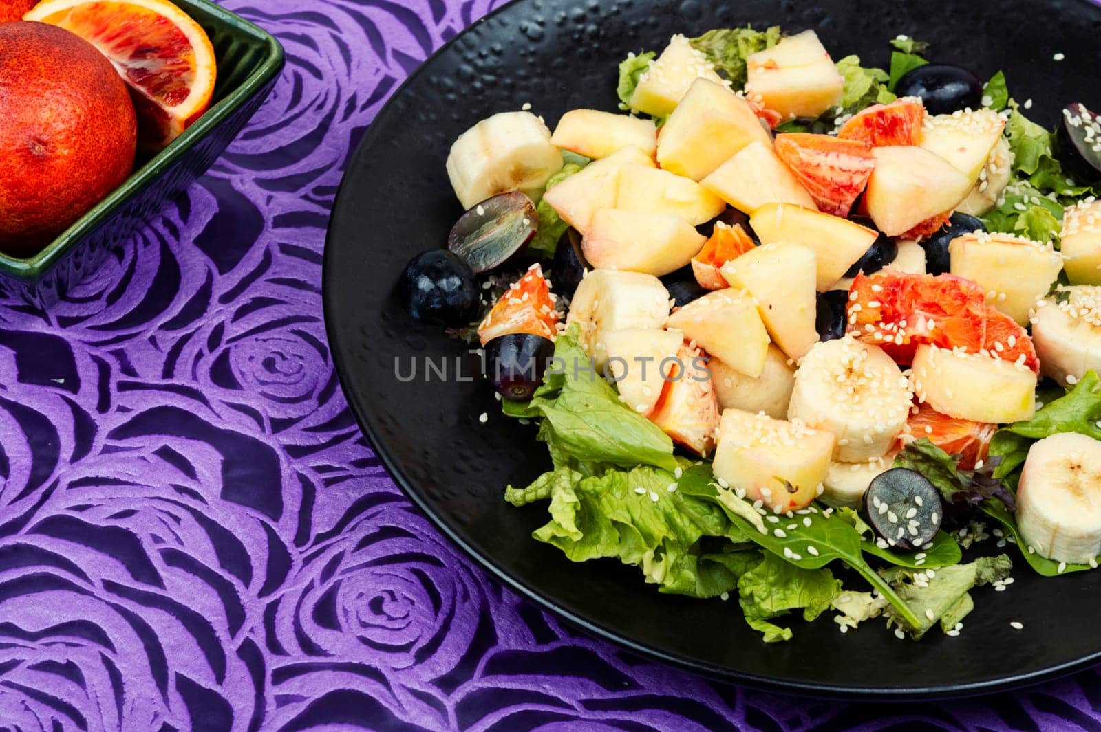Juicy salad of fresh red orange, apple, banana and lettuce. Healthy eating.