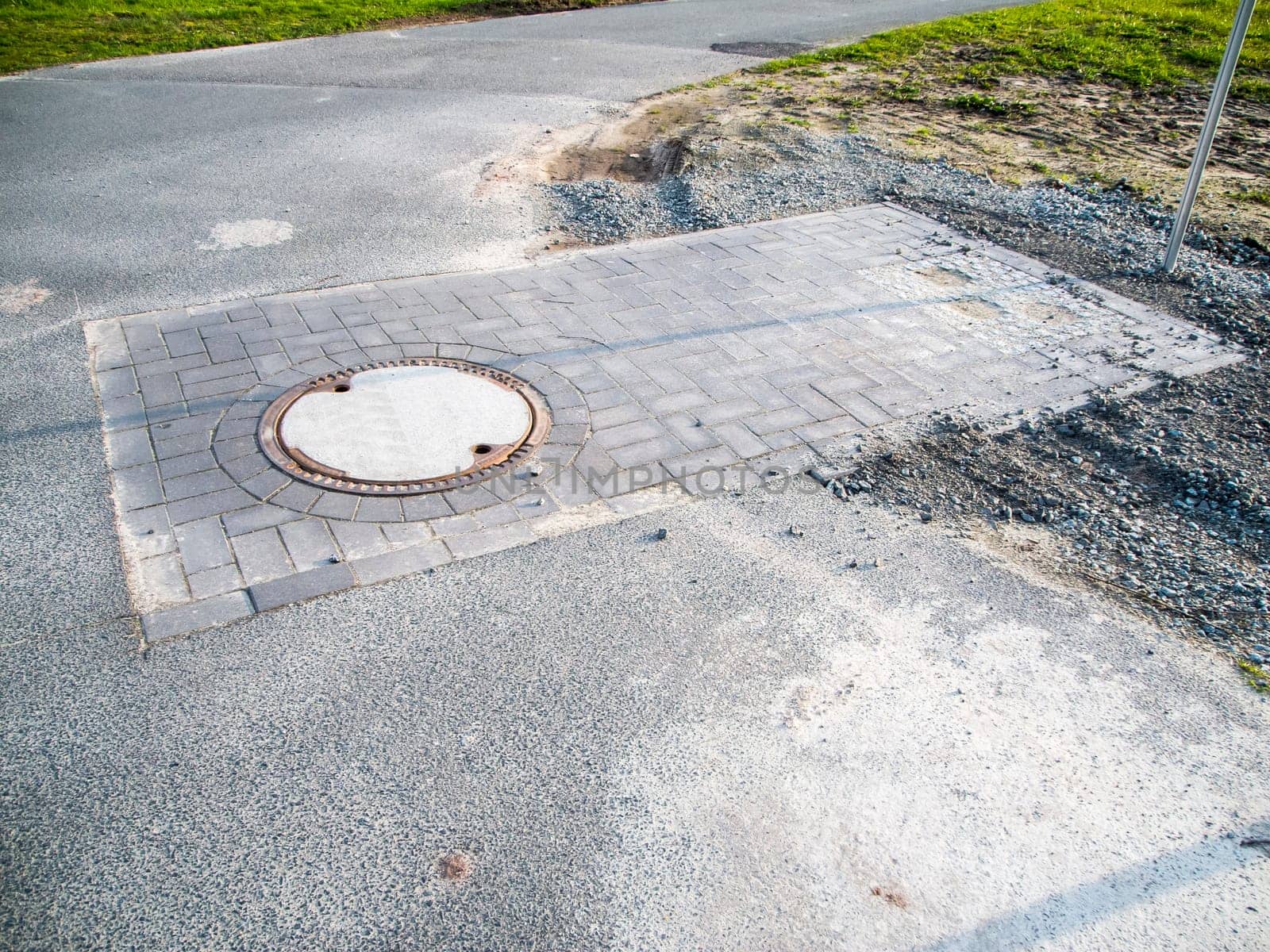 Newly constructed shaft with manhole cover on a rural asphalt road in bavaria.