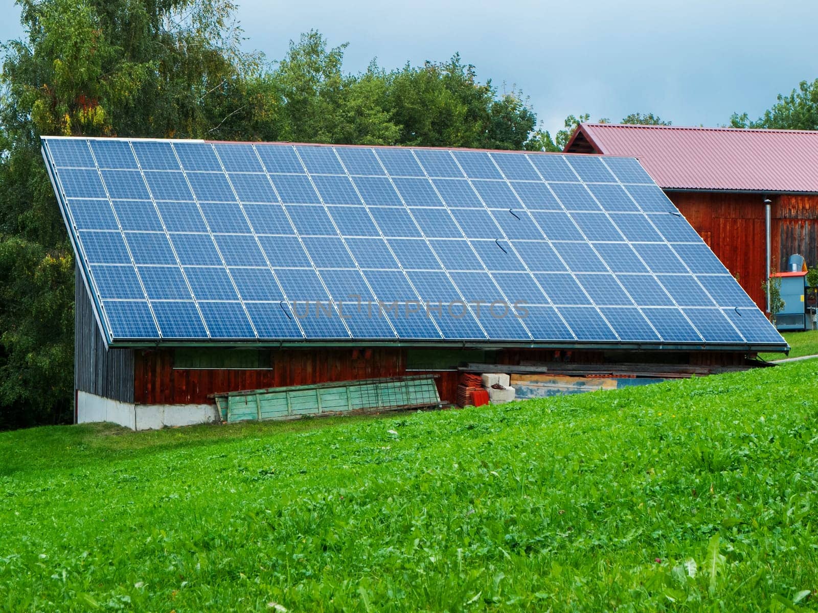 View of a barn roof covered with photovoltaic panels in Bavaria in summer.