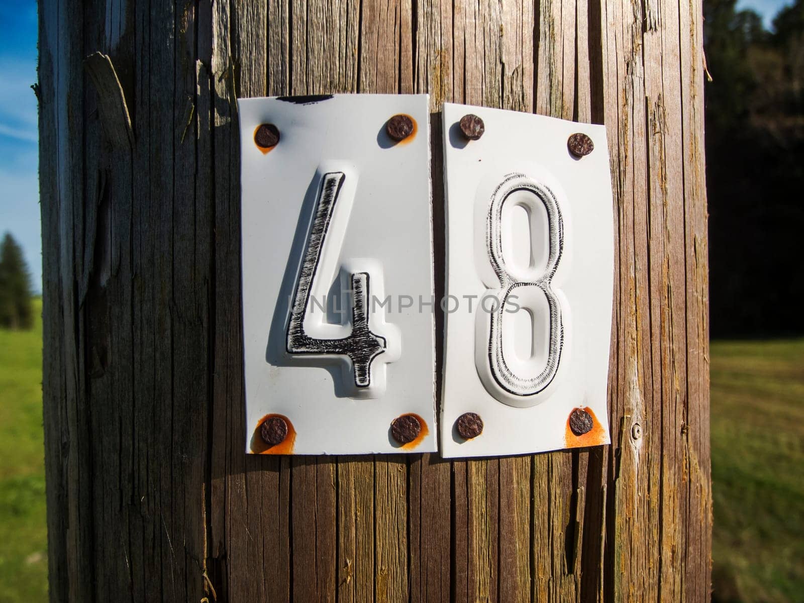 Close-up of a wooden electricity pole with nailed numbers 4 and 8 made of stamped sheet metal.