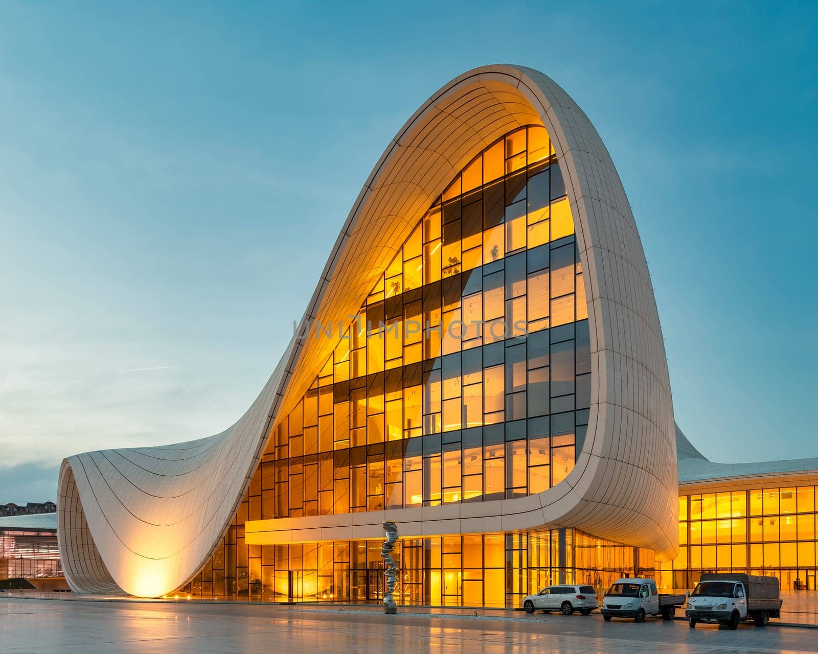 The Heydar Aliyev Centre in Baku, Azerbaijan, glows warmly in the evening with its unique, flowing architecture